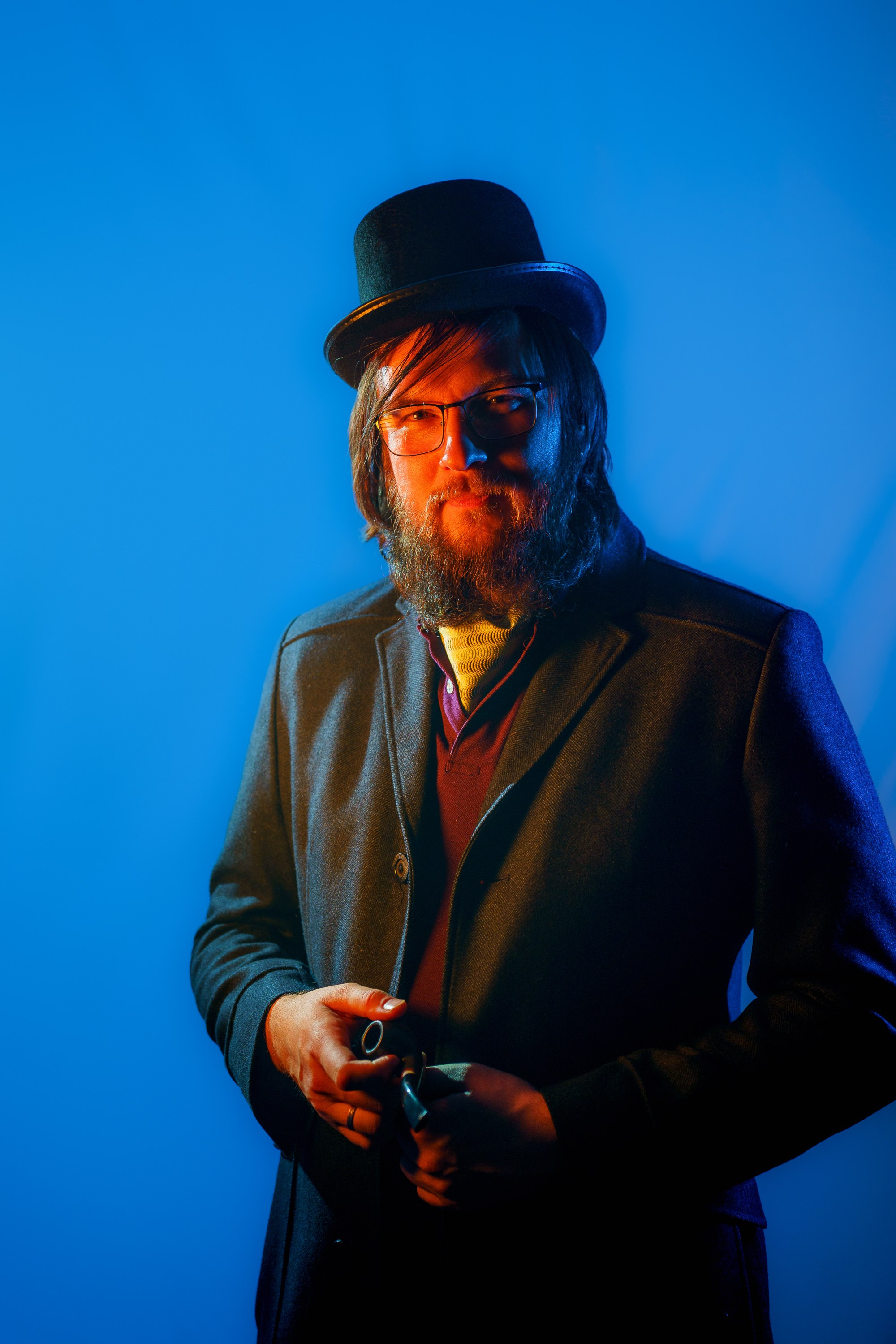 Портрет мужчины в очках и цилиндре с трубкой, синий фон, оранжевый свет