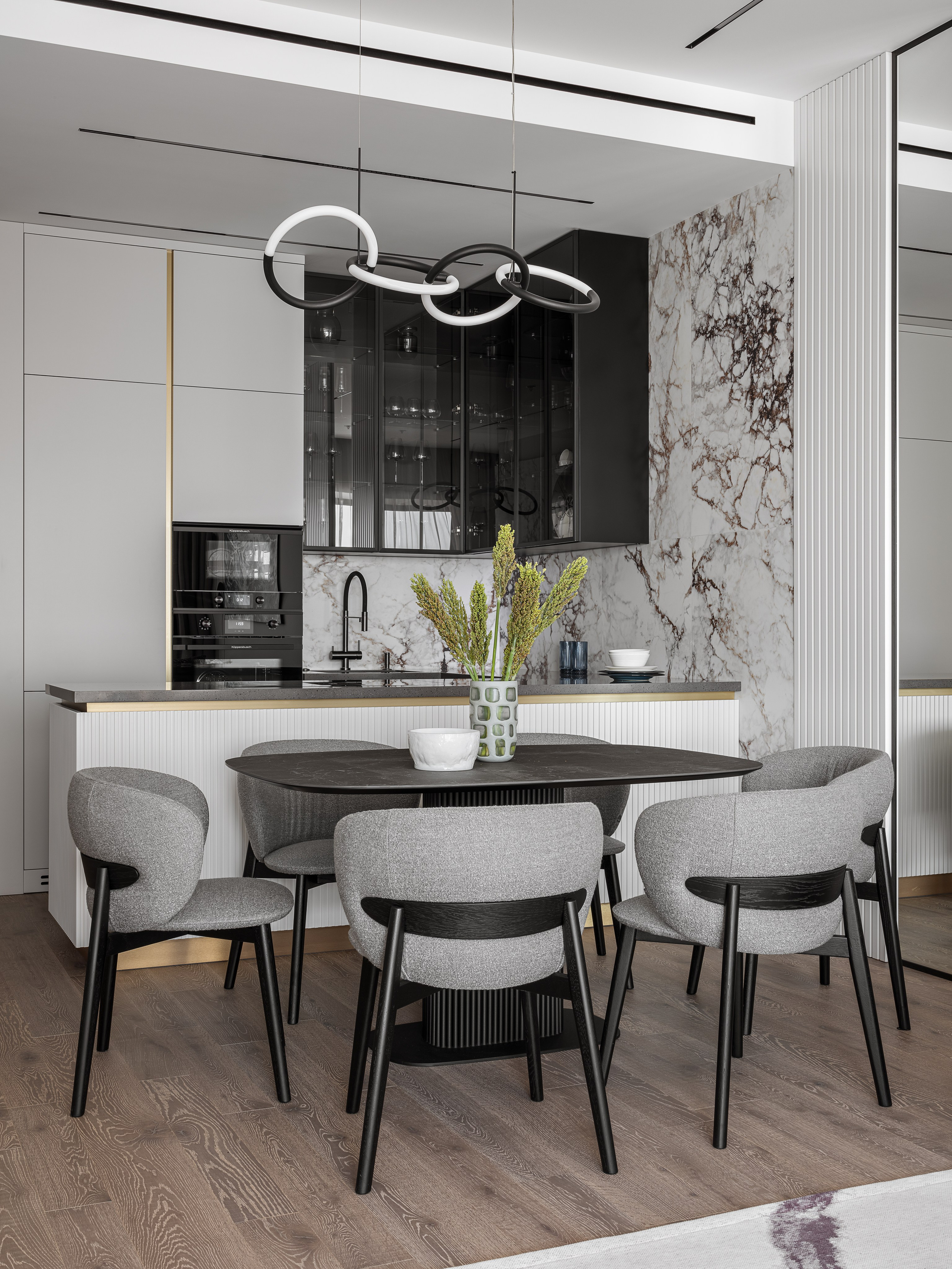 Интерьер кухни-гостиной с акцентом на обеденную зону: черный стол, дизайнерские стулья, оригинальная люстра и кухня с мраморной отделкой. Проект создан Ренатом Байчуковым и Алисей Кириенко, стилист Екатерина Ракитина, фотограф Сергей Денисенко.