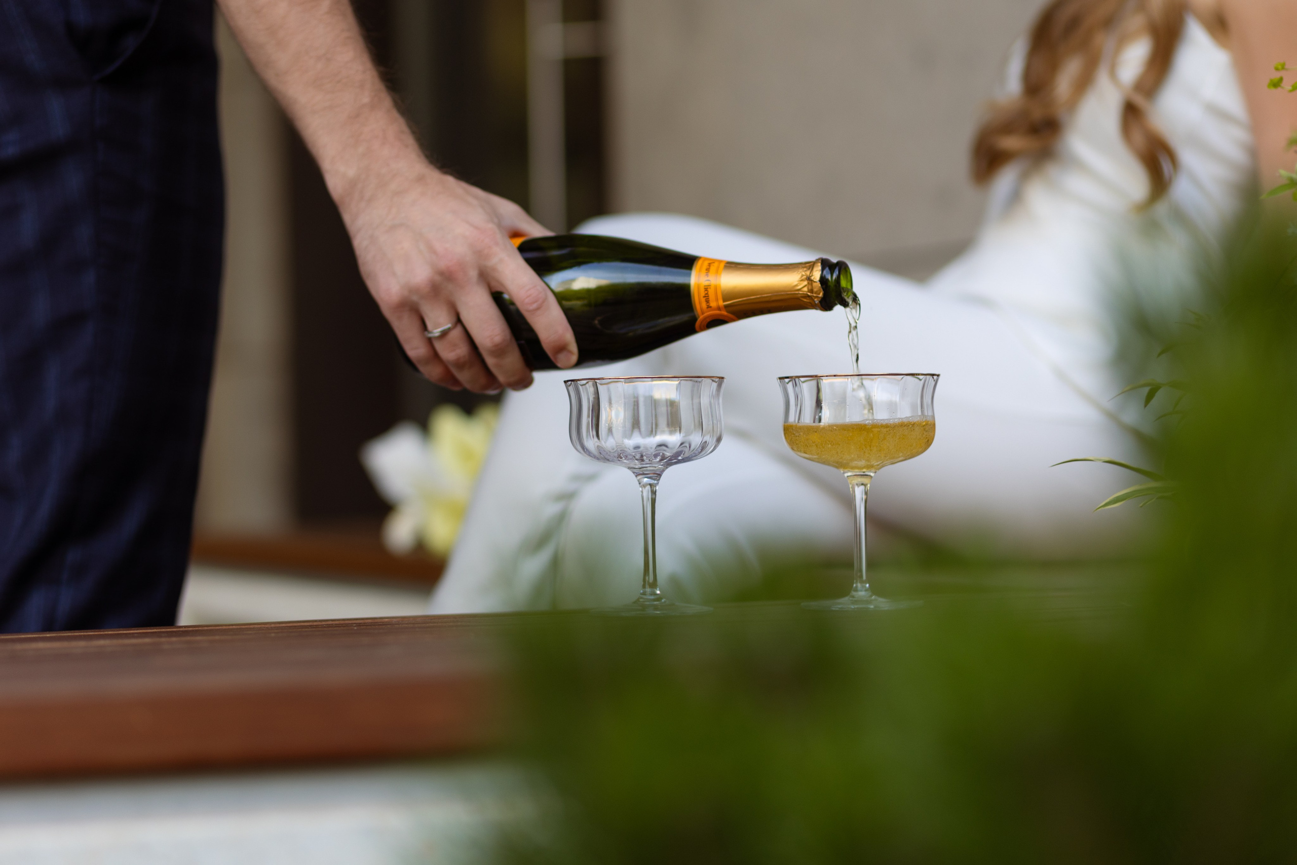 Жених наливает шампанское в бокалы.