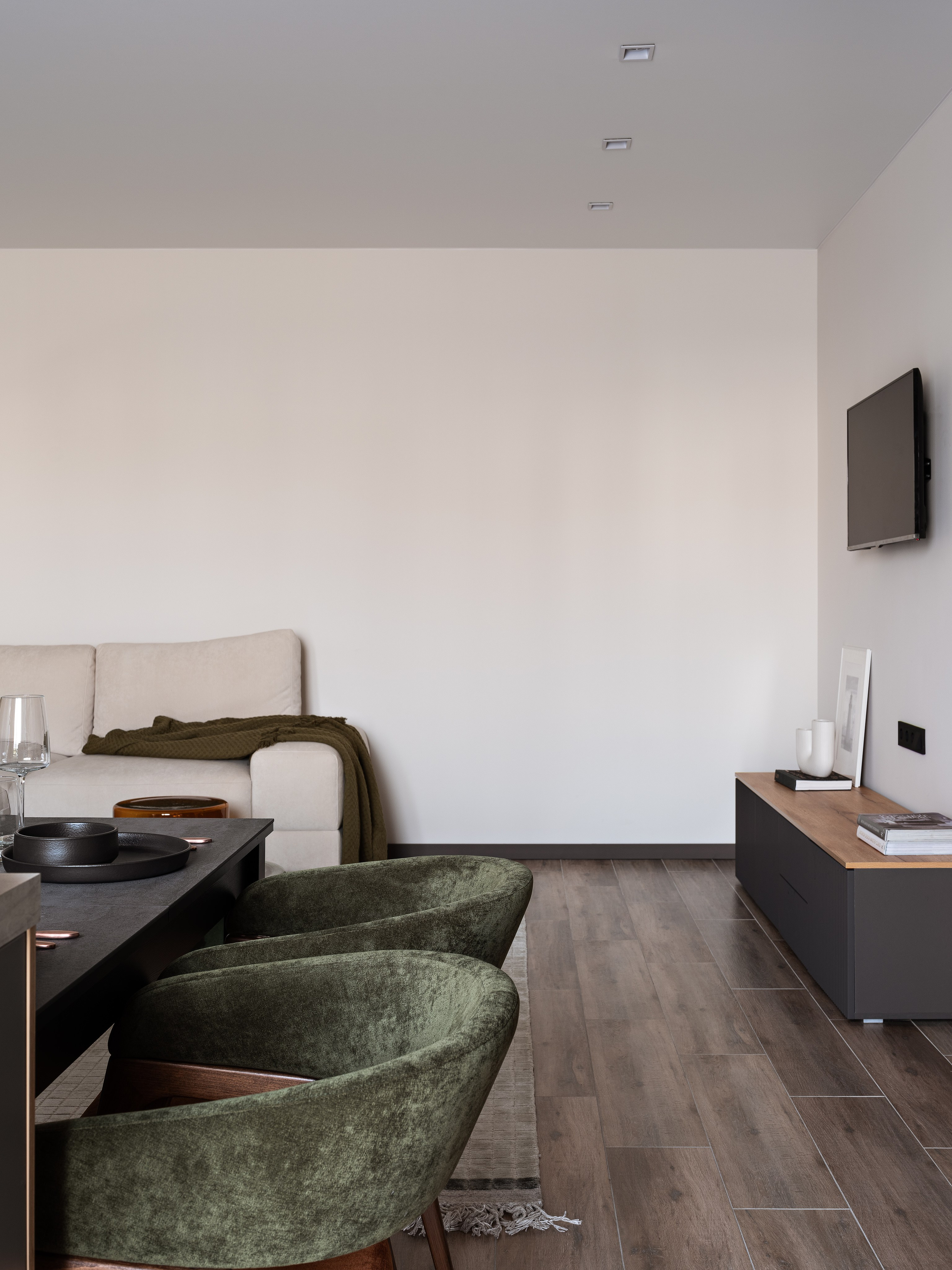 Гостиная с бежевым диваном, деревянным полом и современным телевизором на стене, выполненная в минималистичном стиле; дизайн Екатерины Мищенко, интерьерное фото Сергея Денисенко.