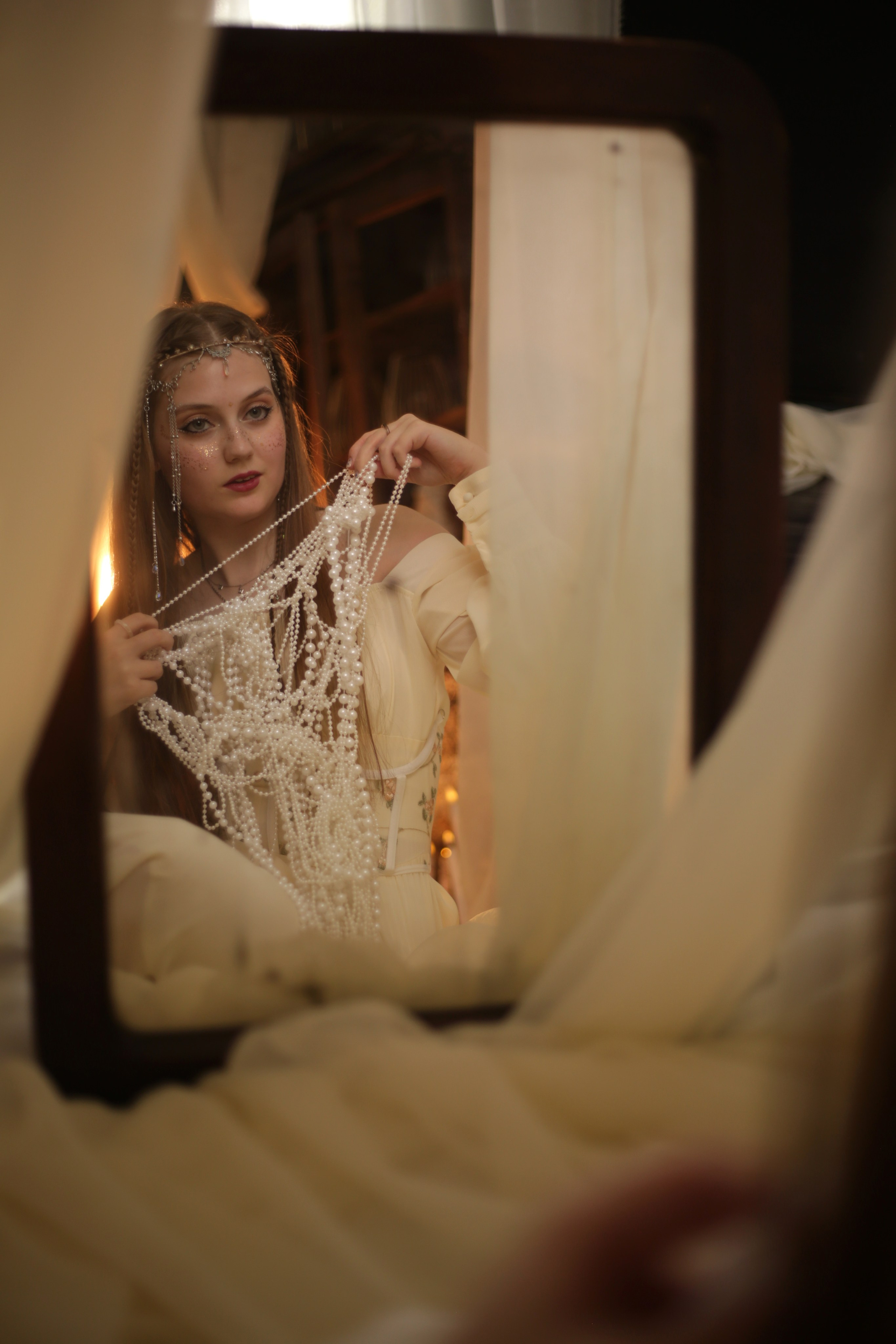 Эльфийская фотосессия в Перми: девушка в белом платье с ушками и головным убором, сидит на кровати под полупрозрачным балдахином