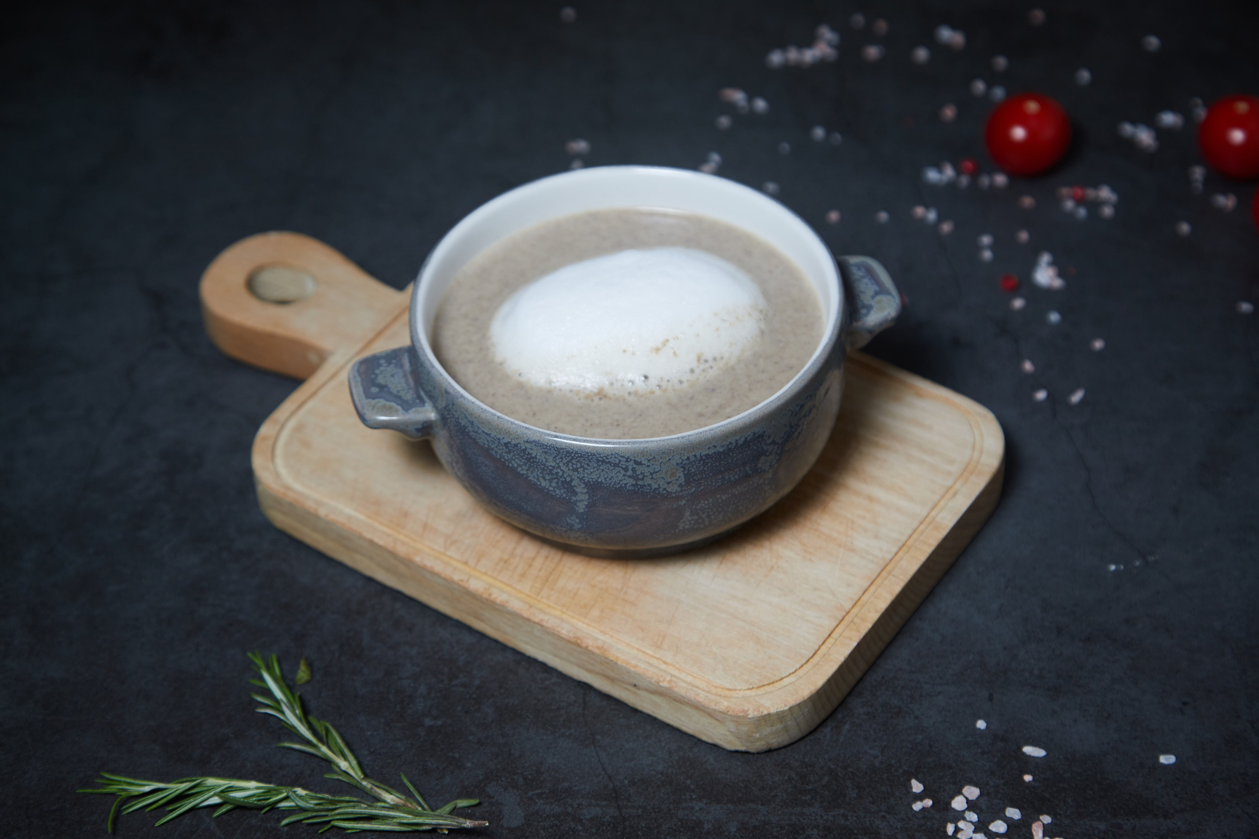 Суп-пюре в керамической пиале на деревянной подставке.