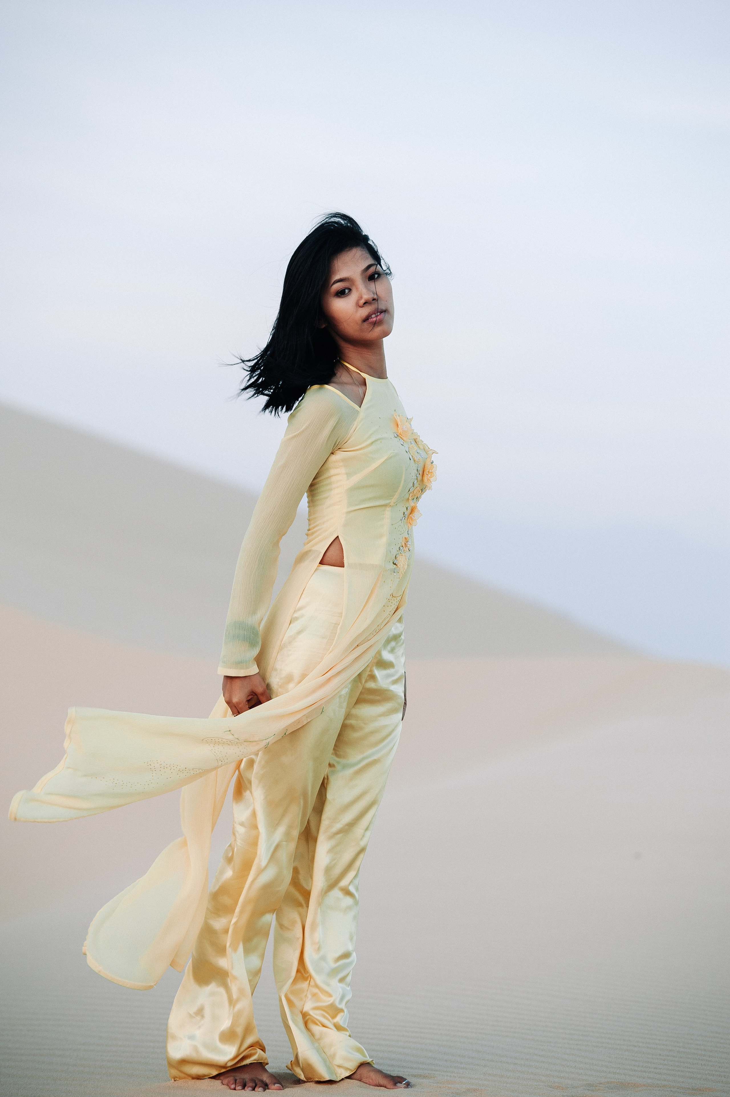 Фотосессия вьетнамской девушки в традиционном вьетнамском костюме Аозай золотого цвета, в дюнах Муине, Вьетнам на закате