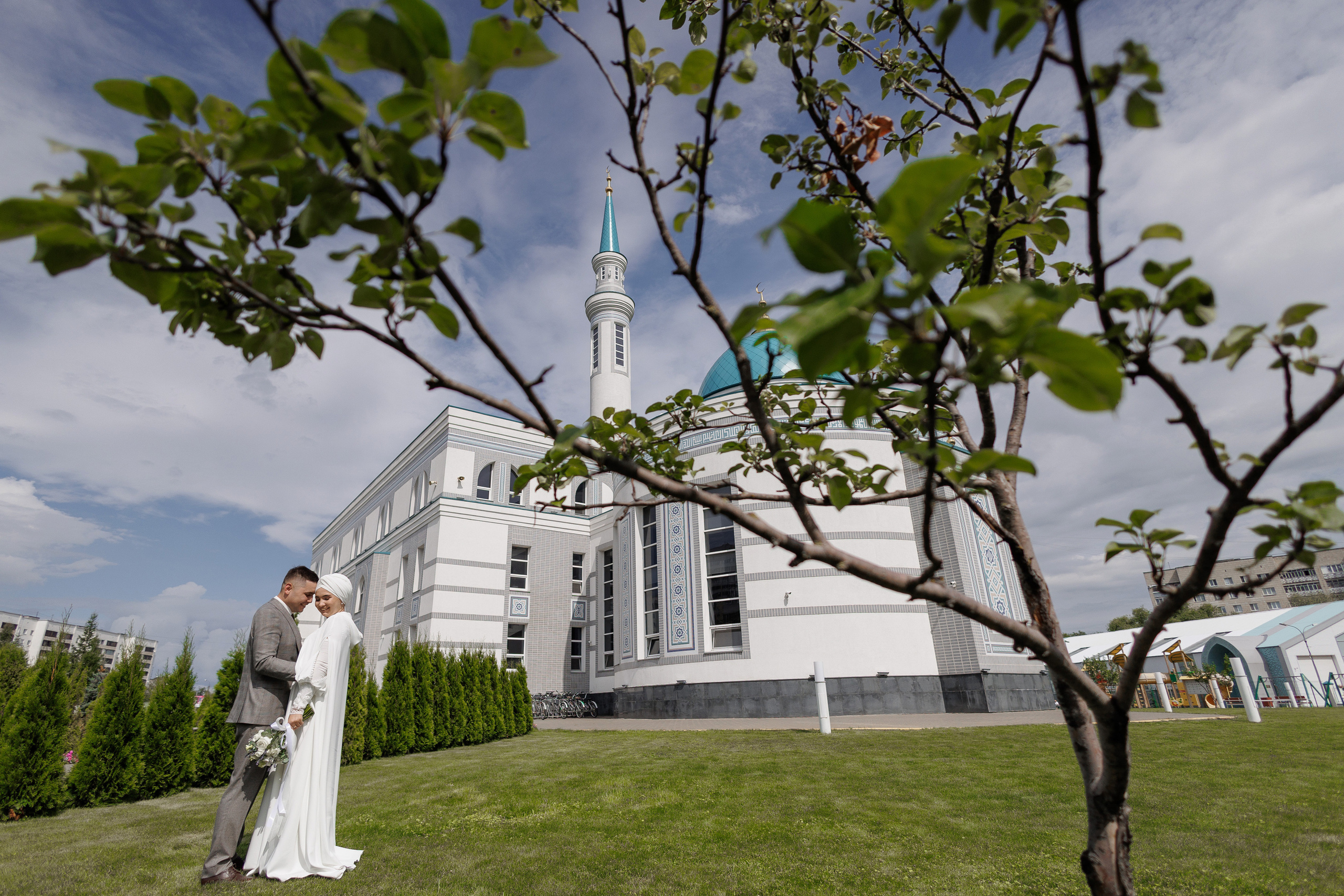 Молодожены на фоне мечети под деревом 