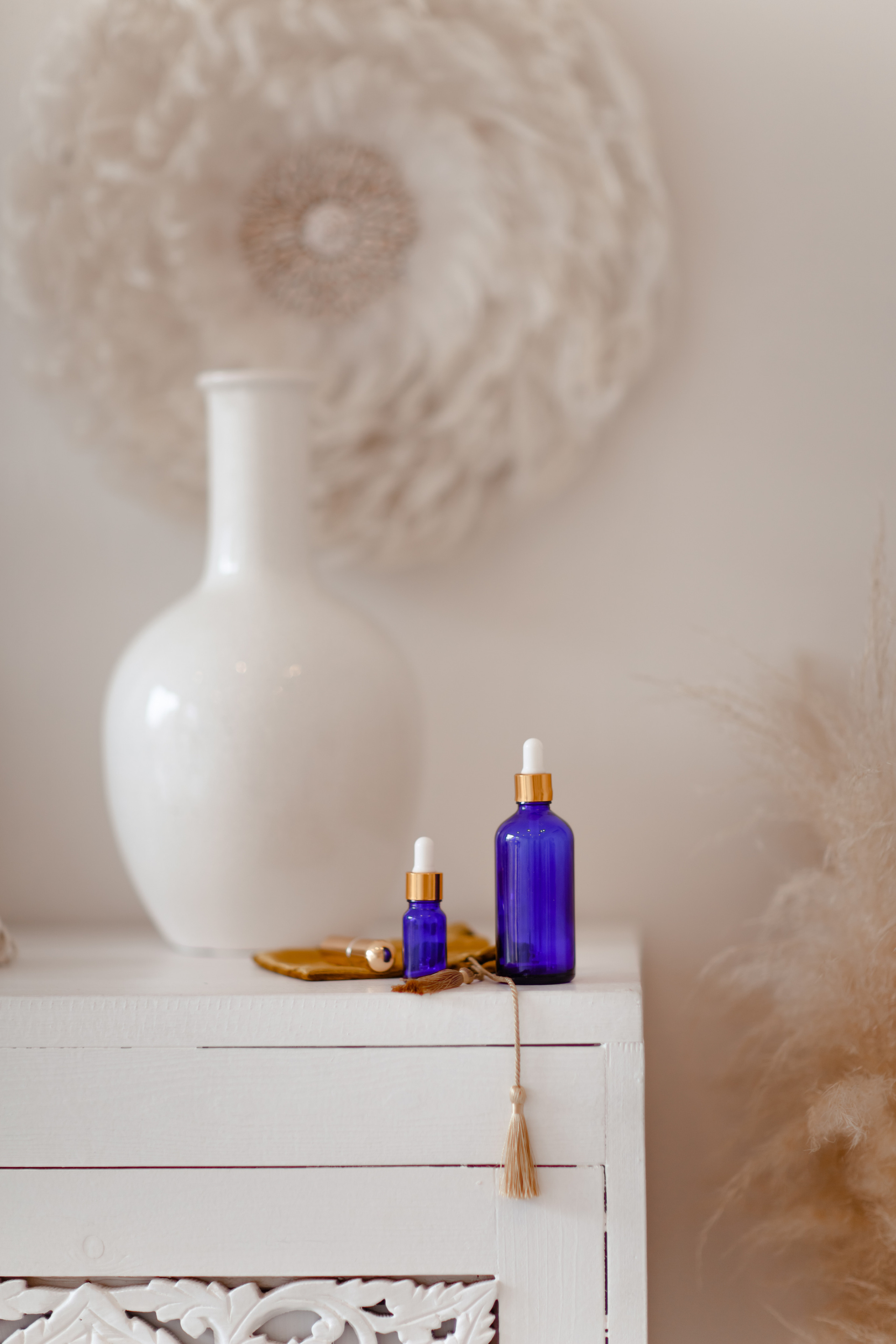 эфирные масла стоит на белом комоде , позади кувшин