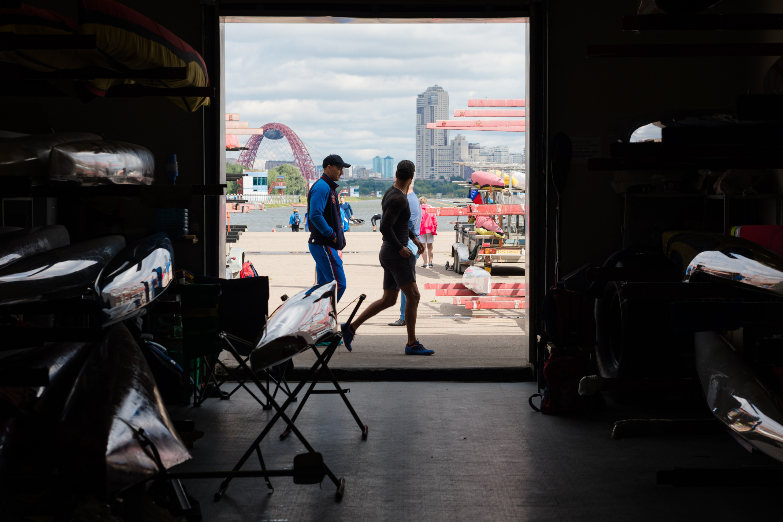 Два человека проходят мимо гаража для лодок на Гребном канале