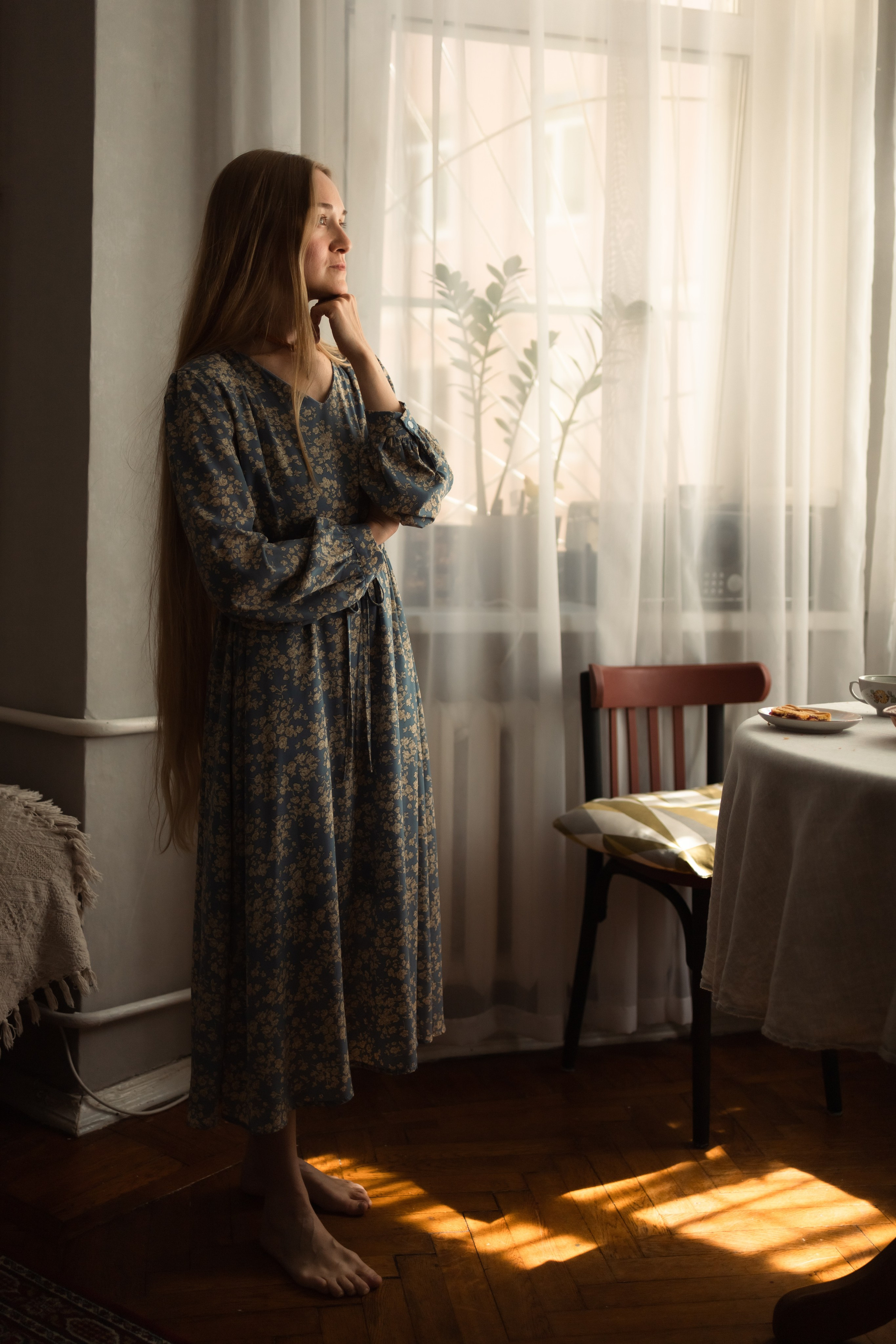 красивая мама стоит задумчиво смотря в окно