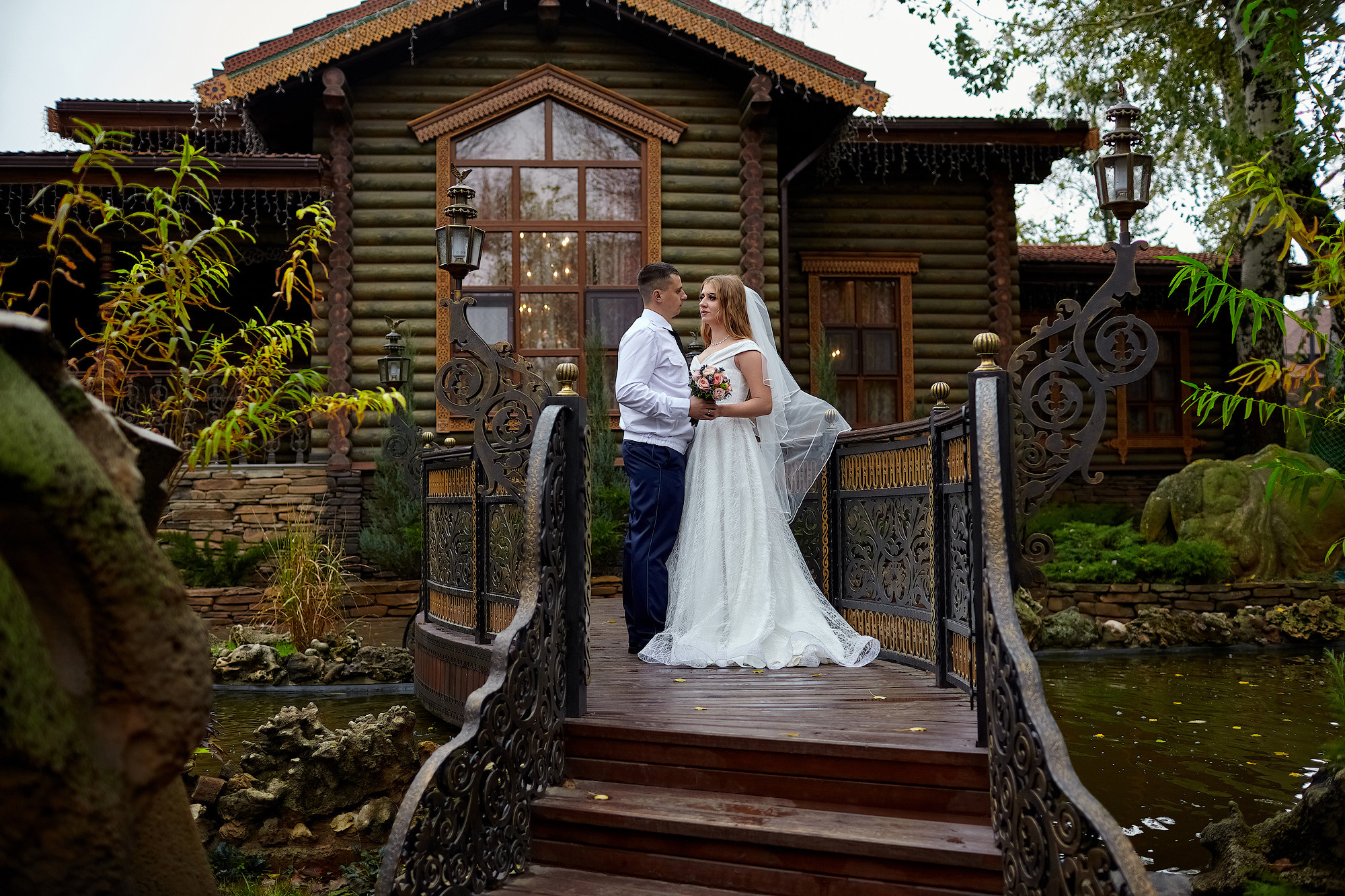 Жених и невеста стоят на кованной лестнице