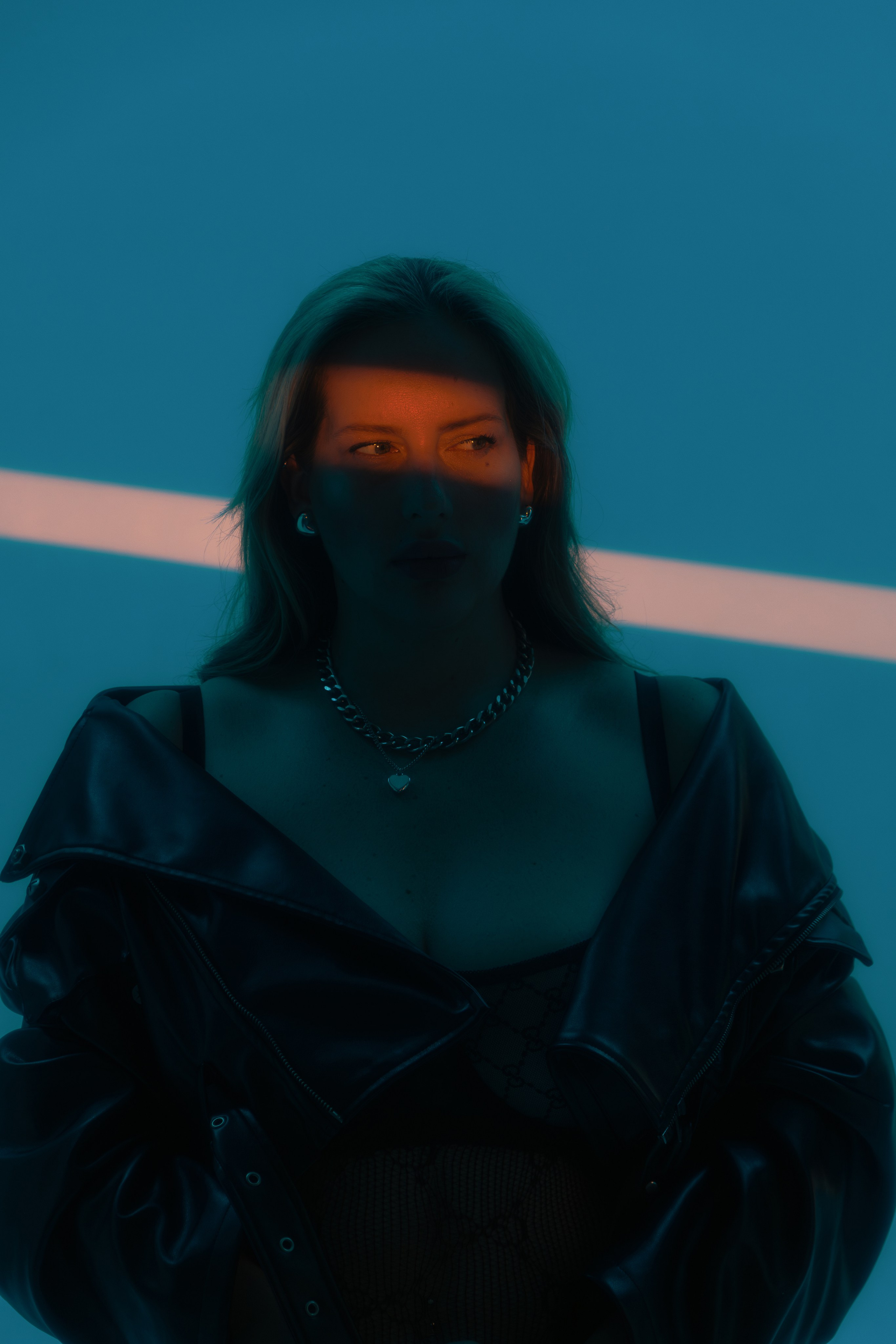 Женский портрет с оранжевой полоской света на лице и синем фоне. Модель плюс сайз в нижнем белье