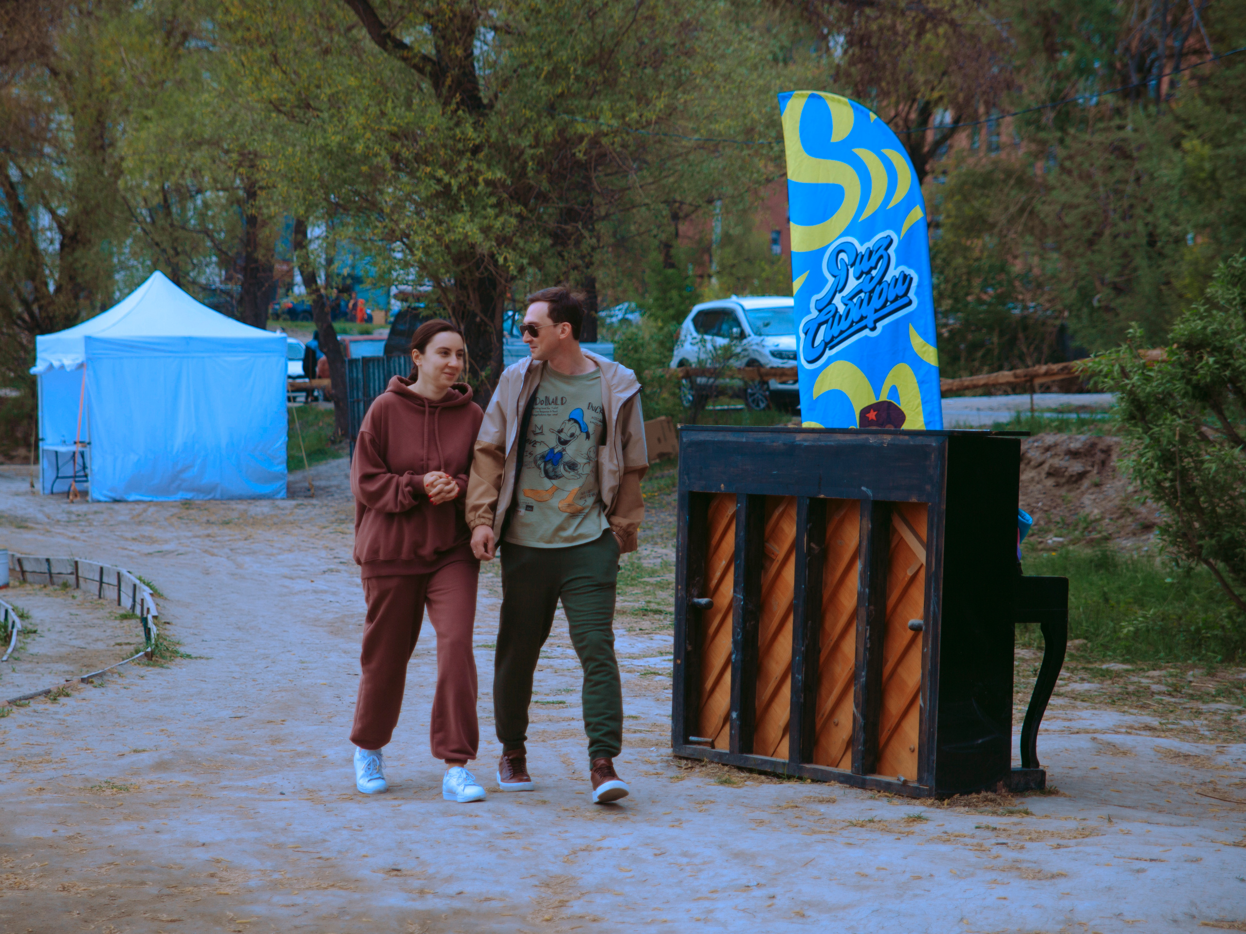 Пара идет по берегу в парке мимо пианино.