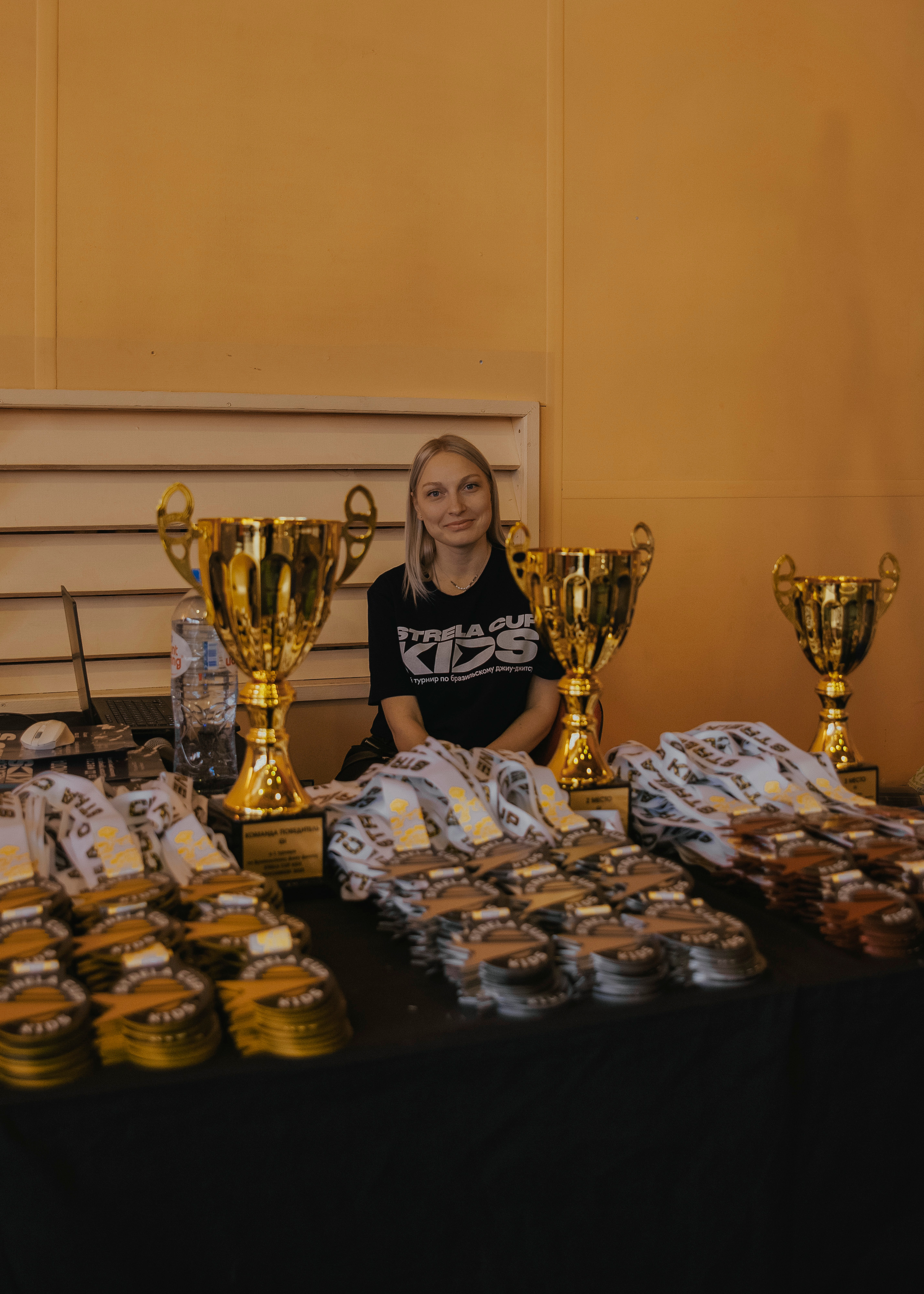 Девушка вручант с золотыми кубками для победителей спортивных соревнований.