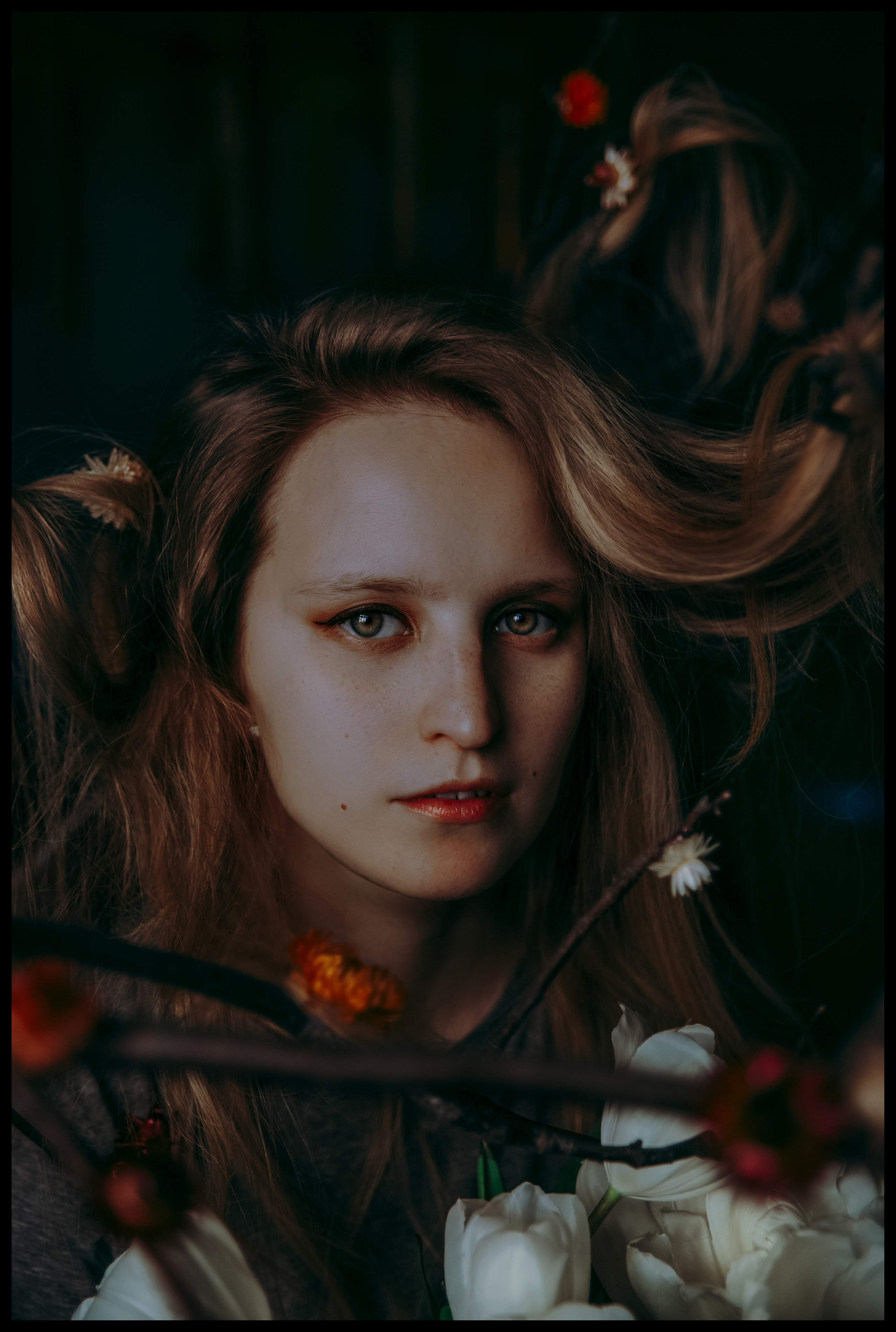 Портрет девушки с цветами в волосах и локонами, запутанными в ветках дерева.
