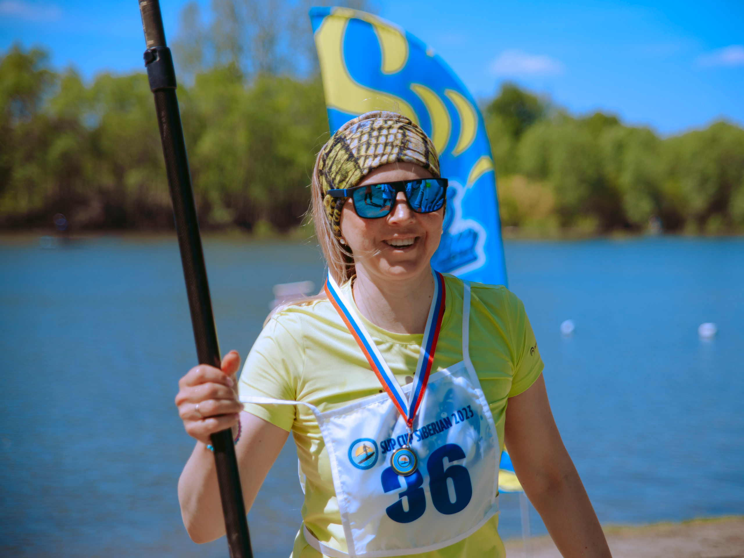 Женщина в синих солнечных очках на фоне воды.