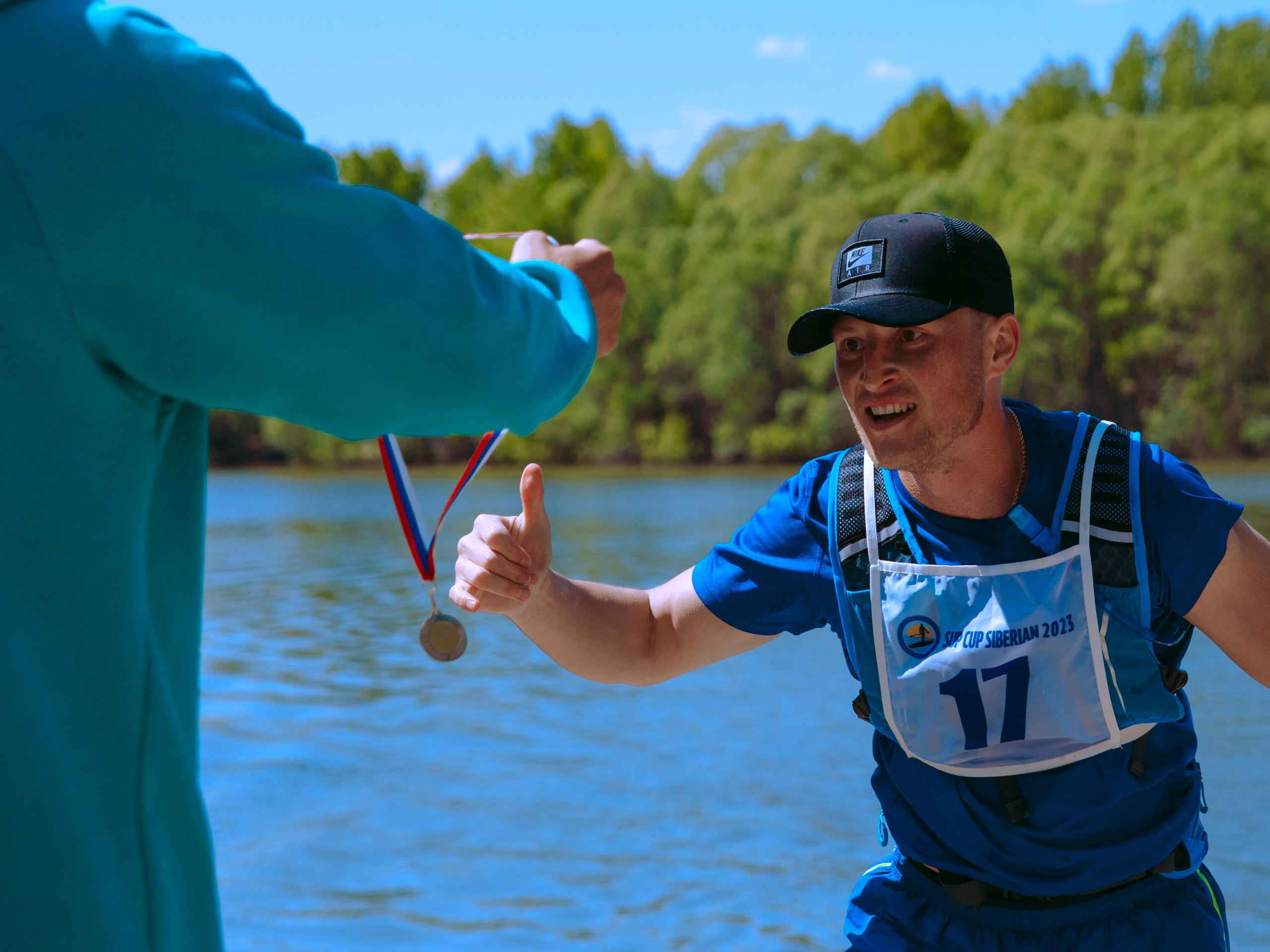 Спортсмен бежит получать медаль с радостью на лице.