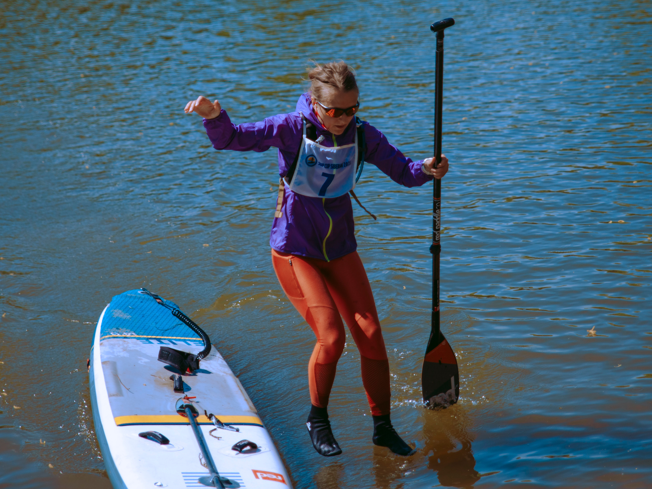 Женщина прыгает с сапа в воду.