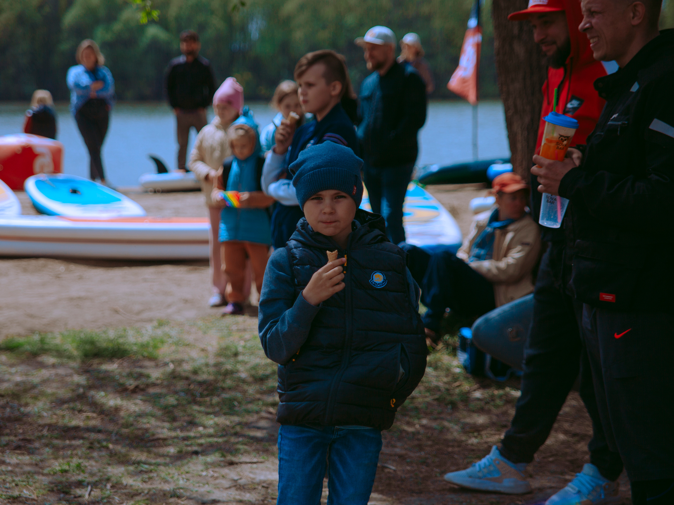 Мальчик ест мороженое в парке.