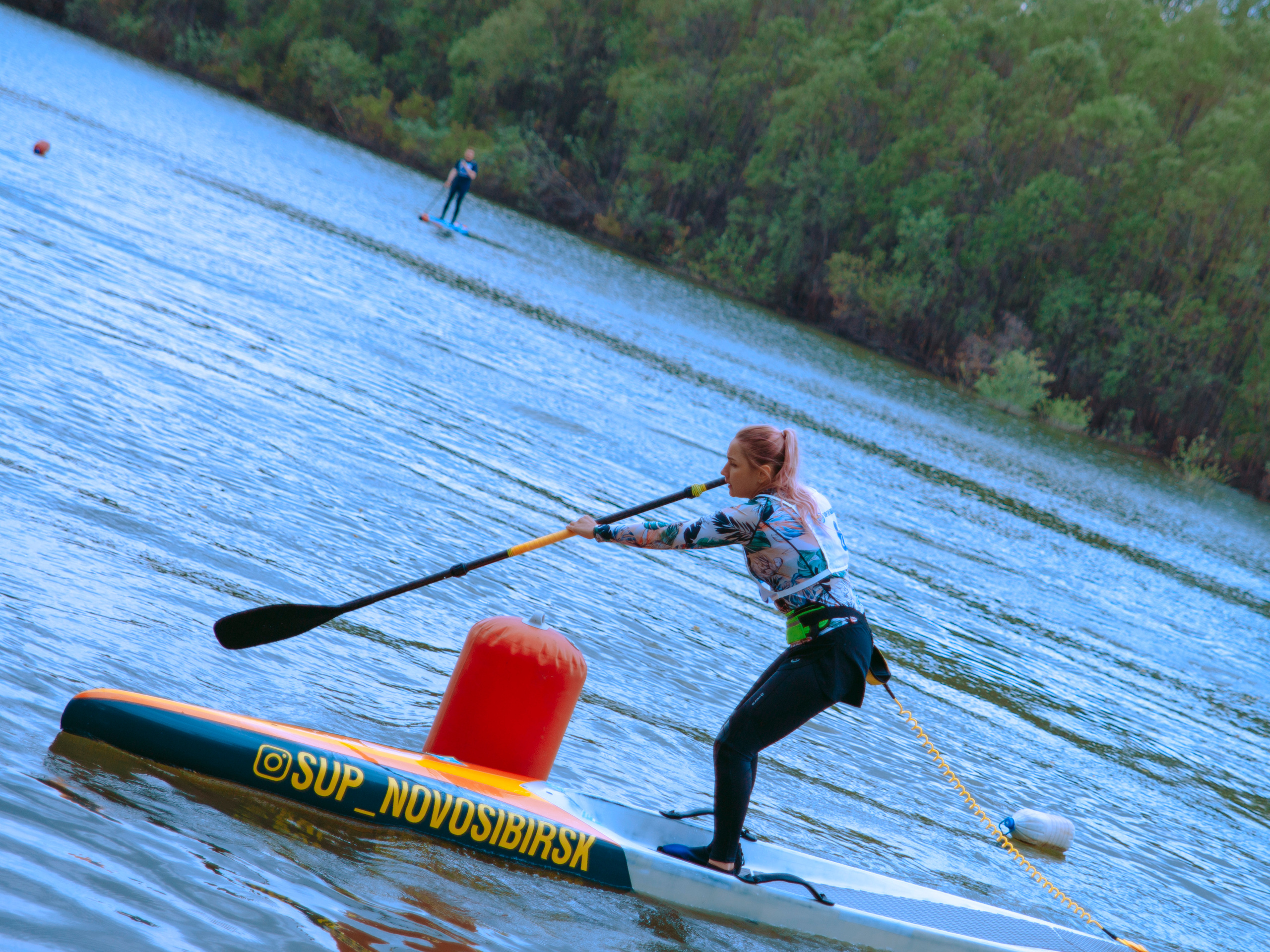 Сап-серфингистка гребет веслом.