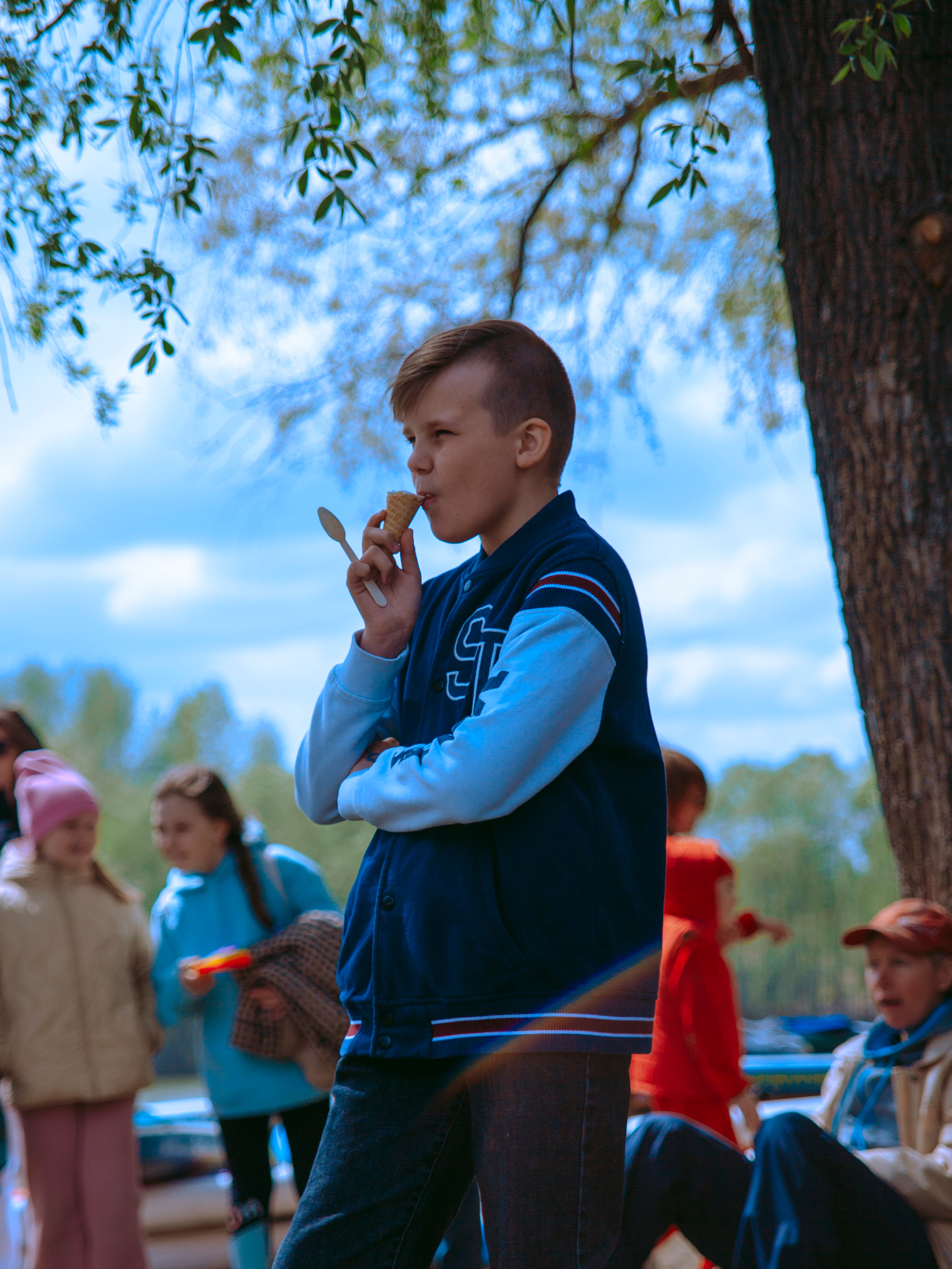 Мальчик ест мороженое в парке.