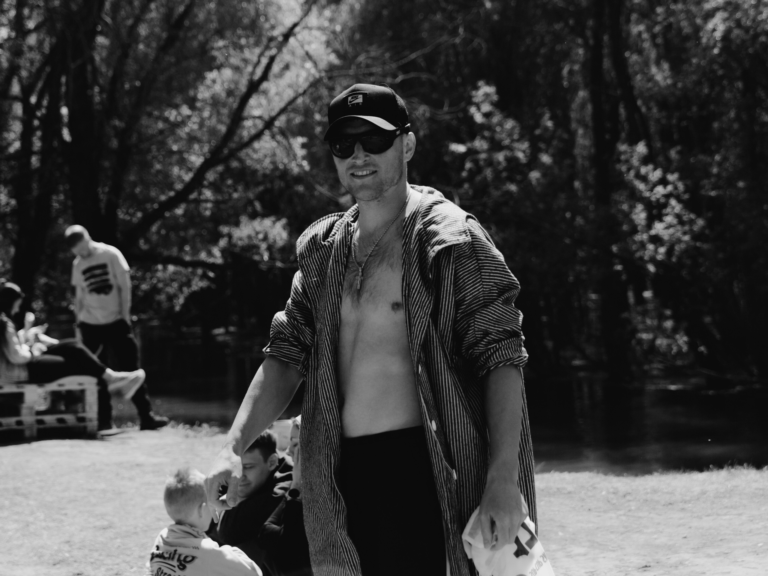 Парень в расстегнутой рубашке гуляет по берегу.