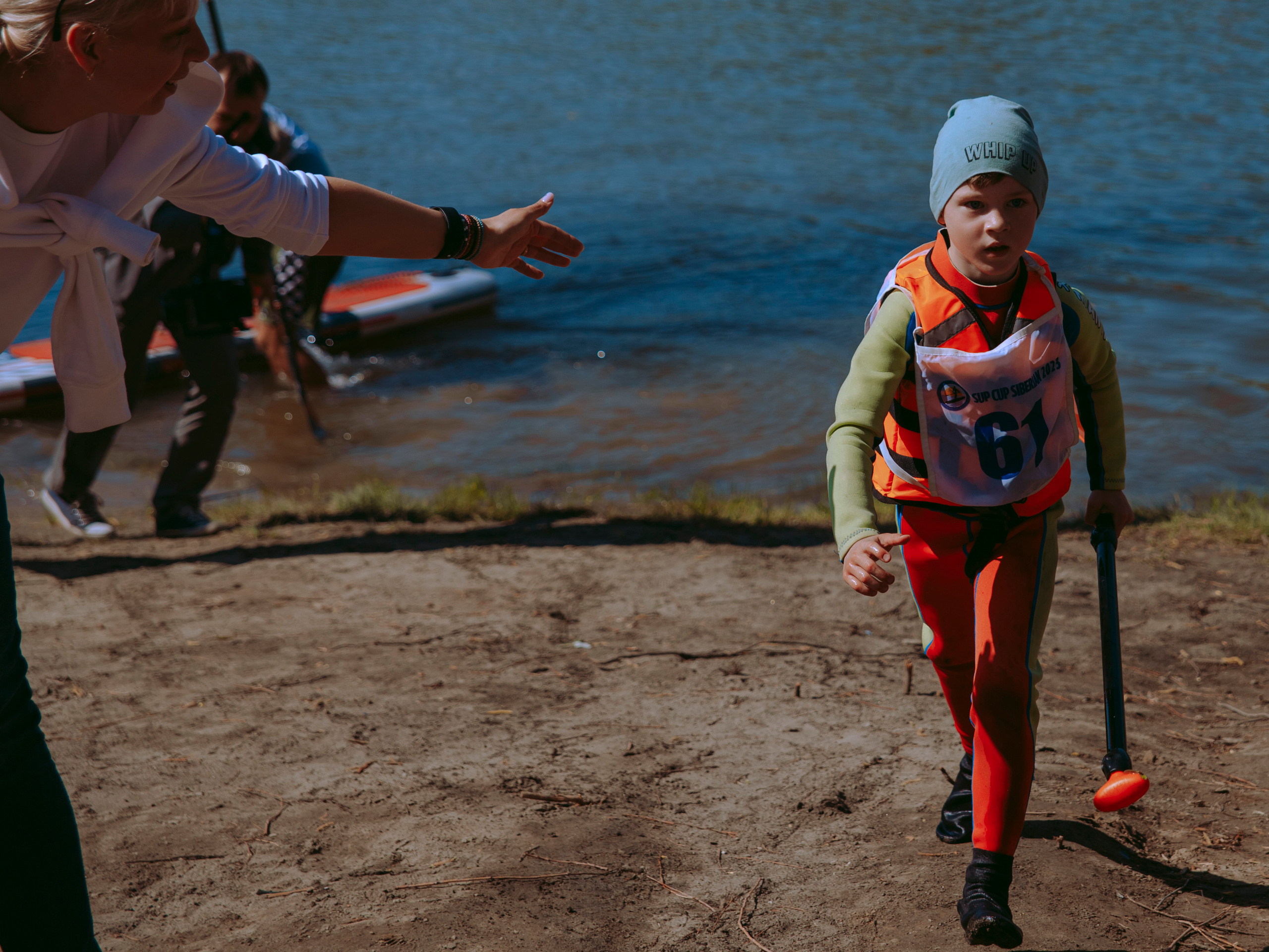 Мальчик серфер выходит из воды.