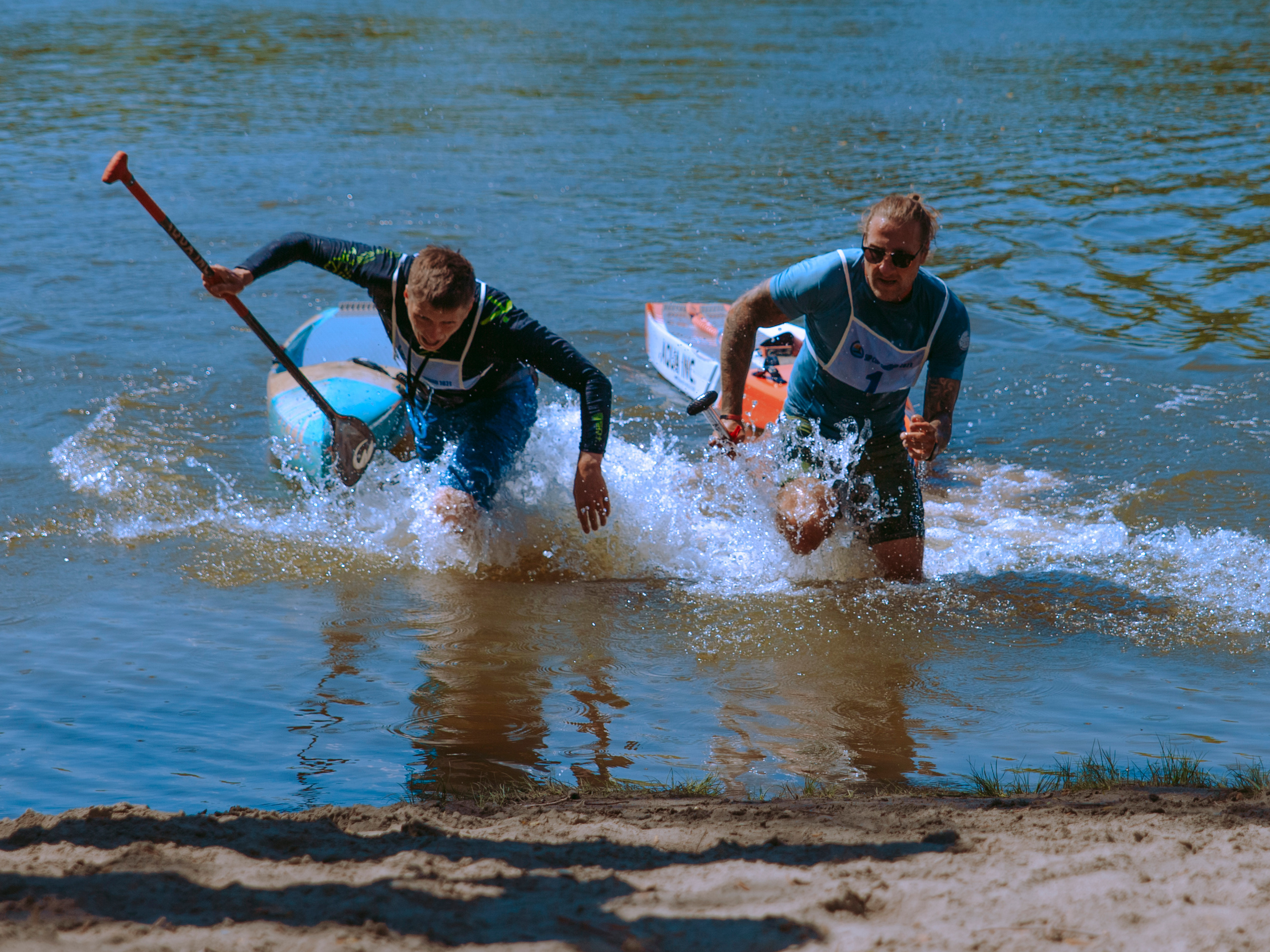 Мужчины выбегают из воды и борются за победу.