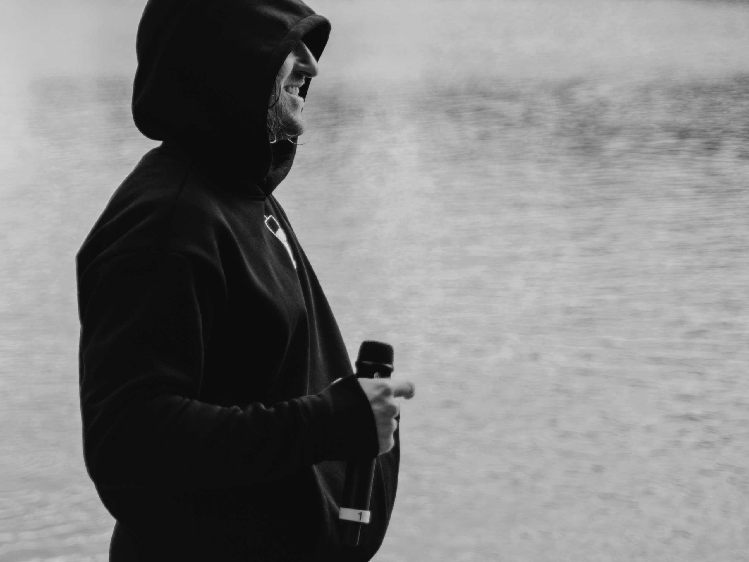 Мужчина в капюшоне на фоне воды.