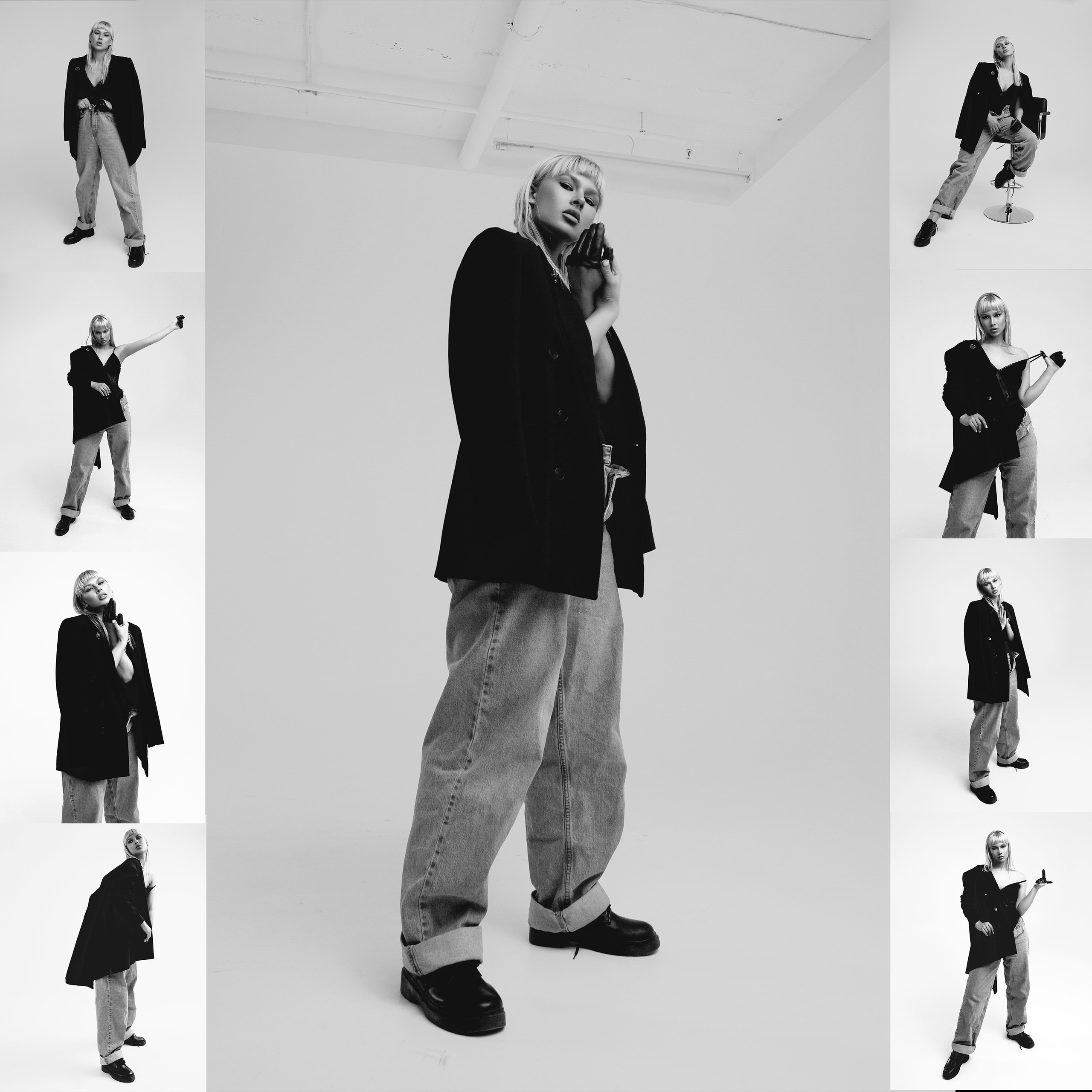 Девушка в джинсах бананах и черном оверсайз пиджаке стоит на белом фоне в циклораме.