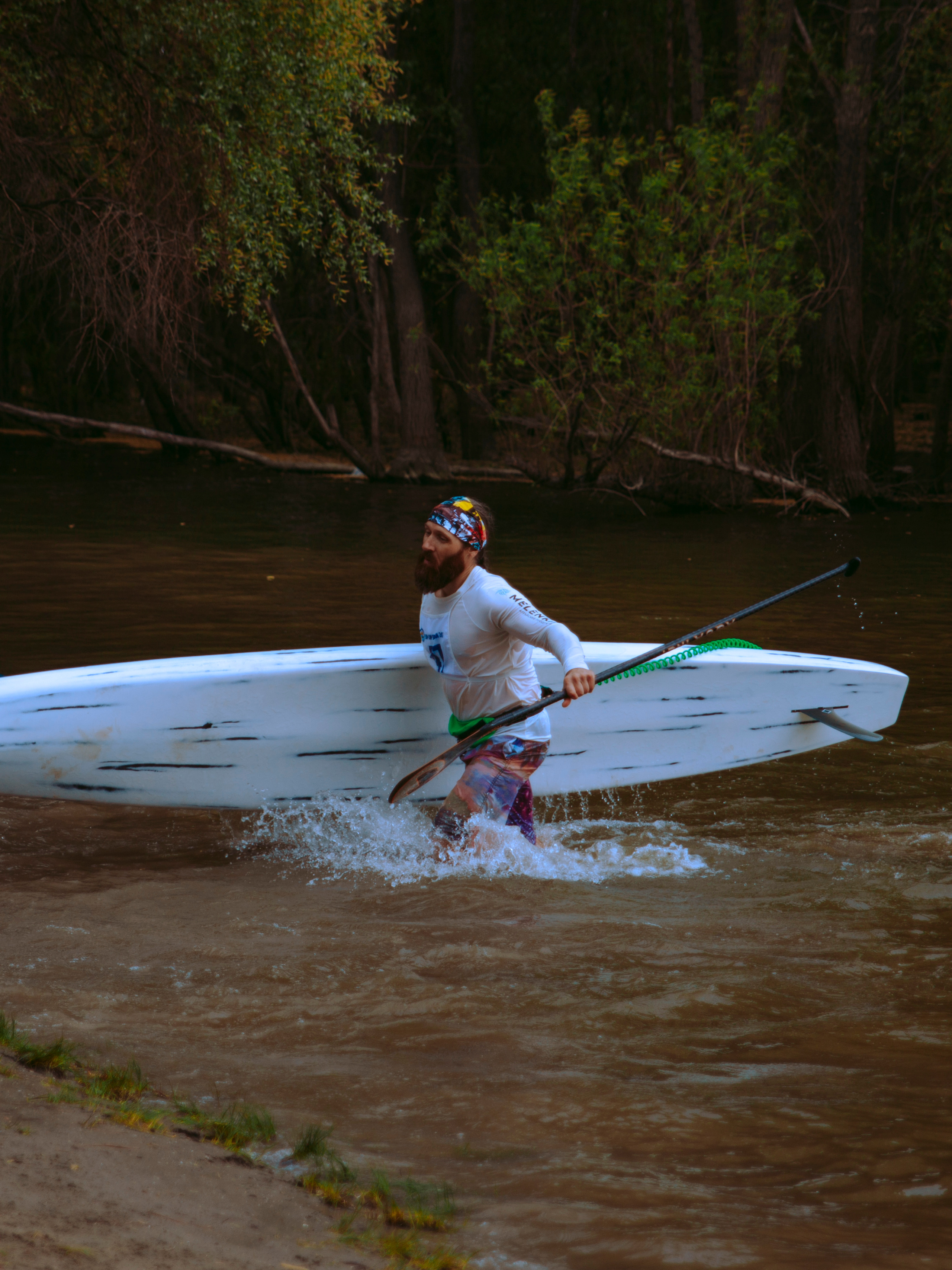Мужчина серфер выходит из воды с сапом.