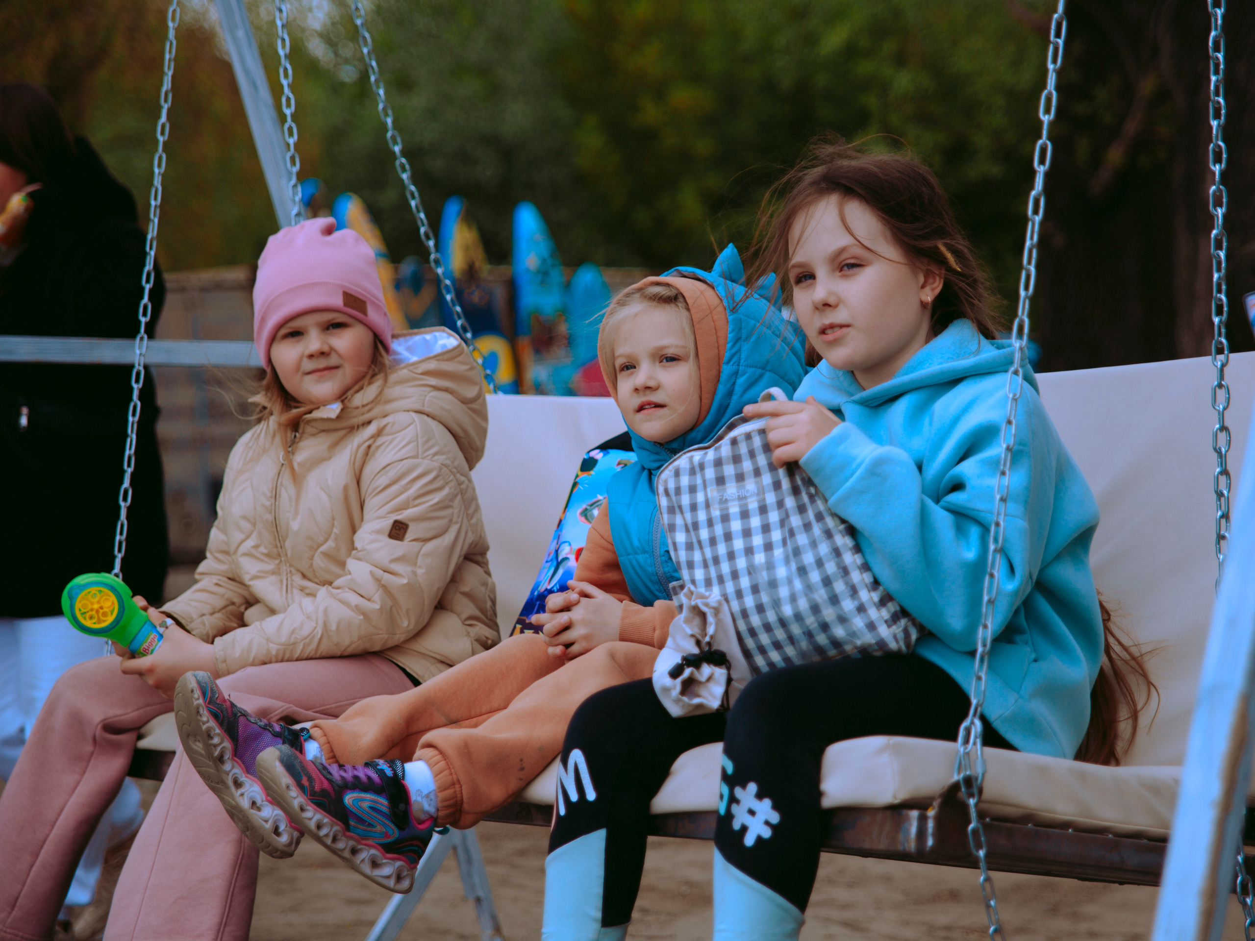 Дети качаются на качелях на свежем воздухе.