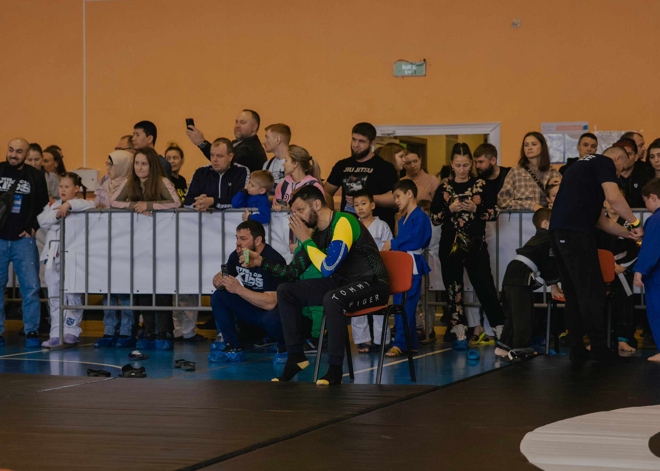 Тренер поддерживает и переживает на детском турнире по джиу-джитсу.