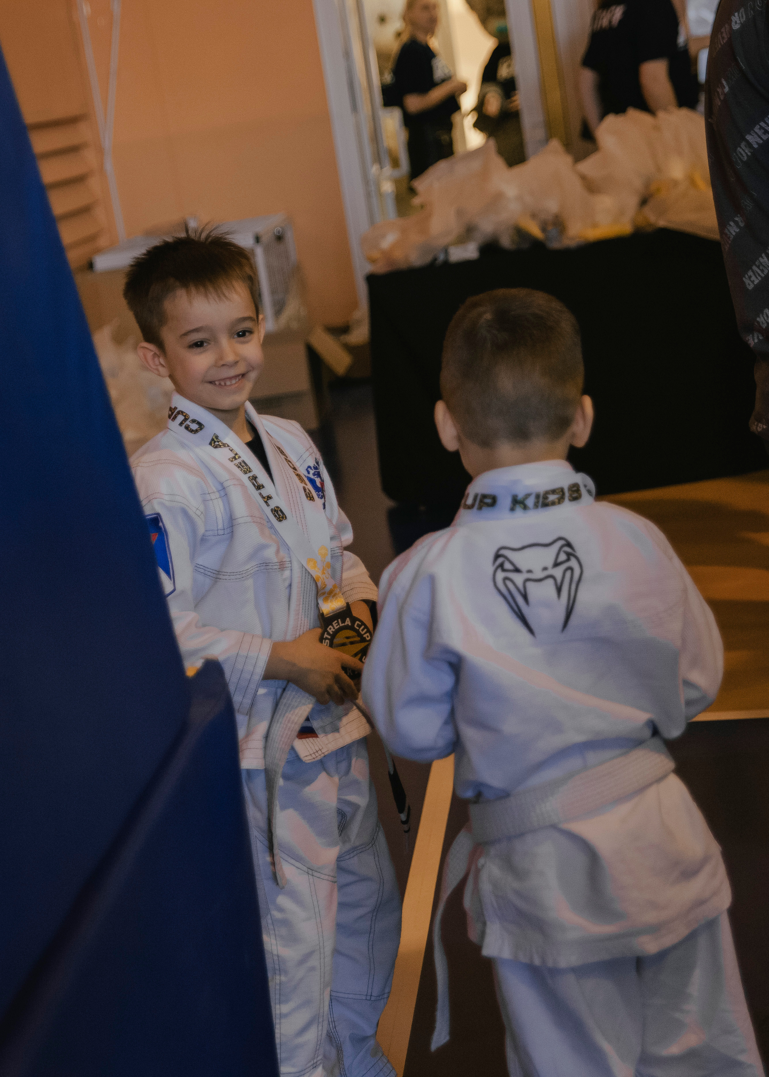 Дети общаются и смеются на детском турнире по джиу-джитсу.