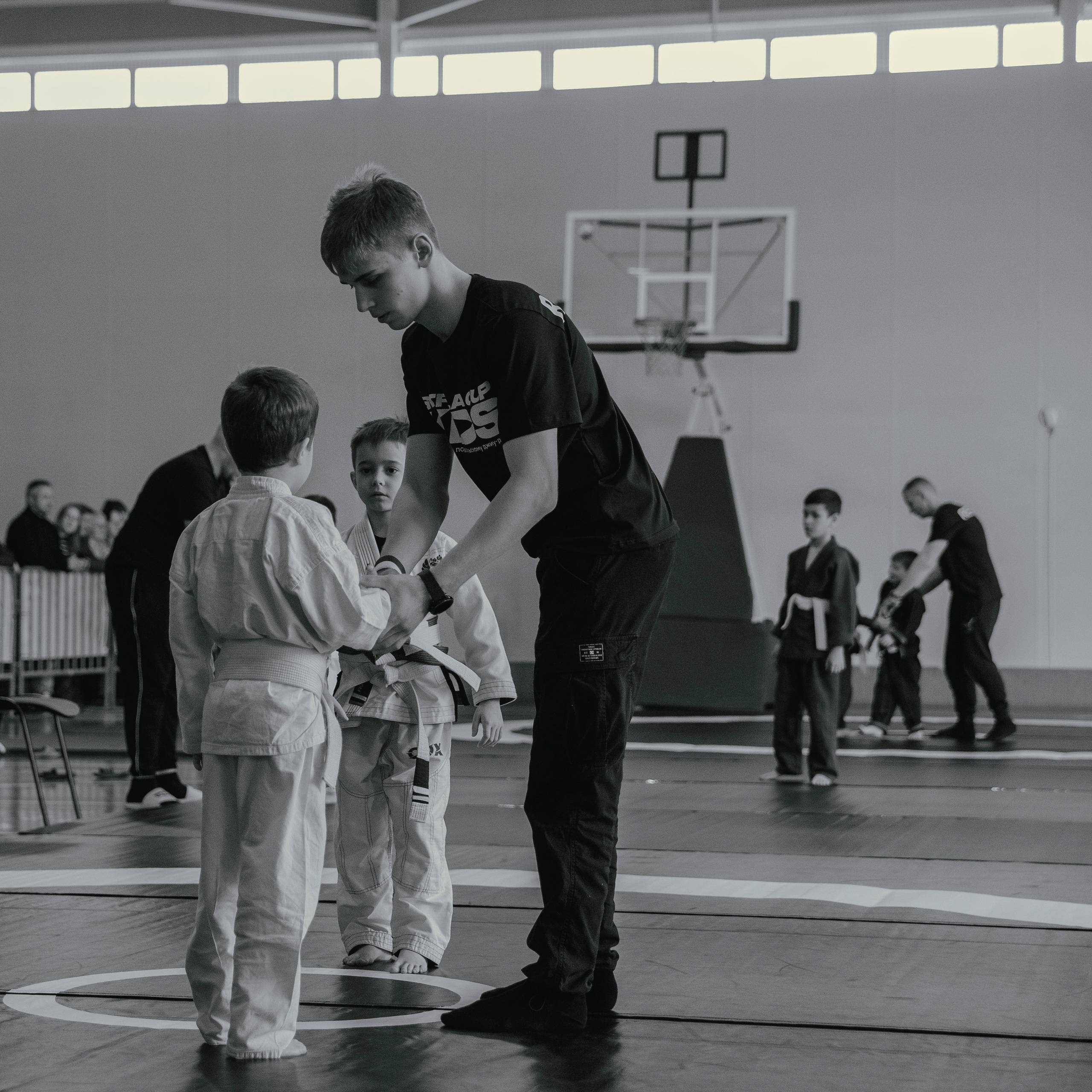 Дети в белых кимоно на детском турнире по джиу-джитсу.