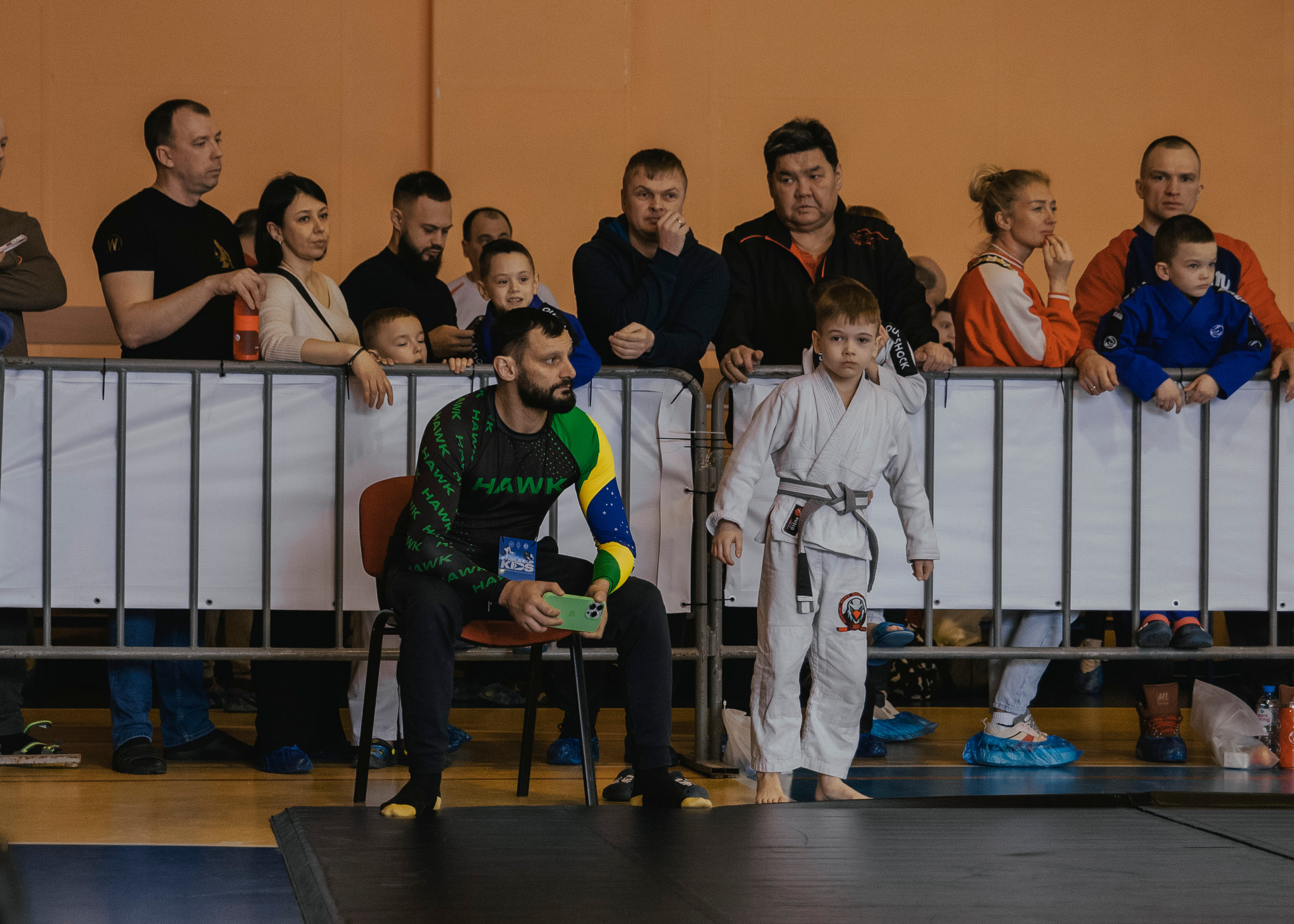 Тренер и подопечный в белом кимоно на детском турнире по джиу-джитсу.