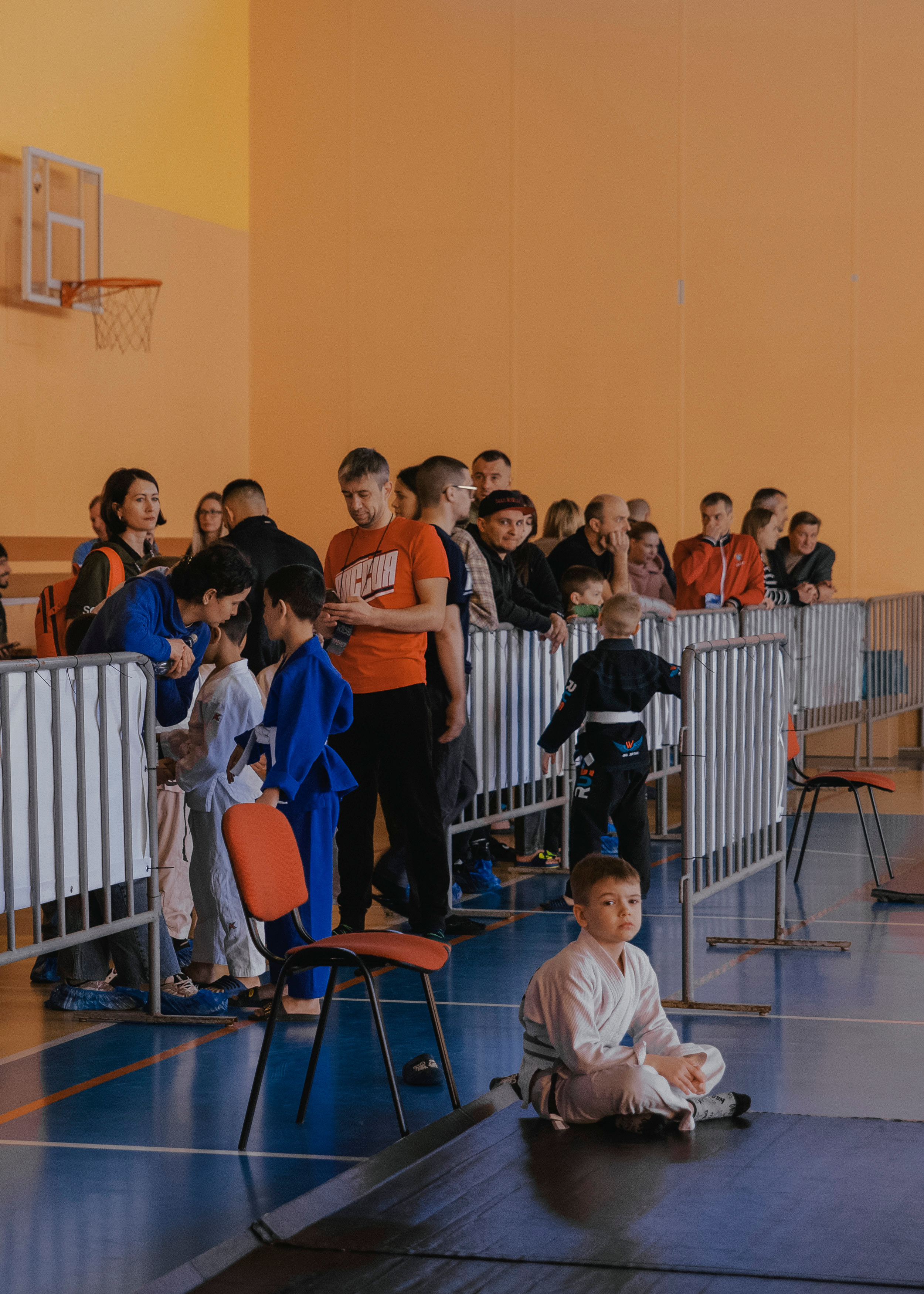 Мальчик каратист джиу-джитсу сидит в углу ковра.