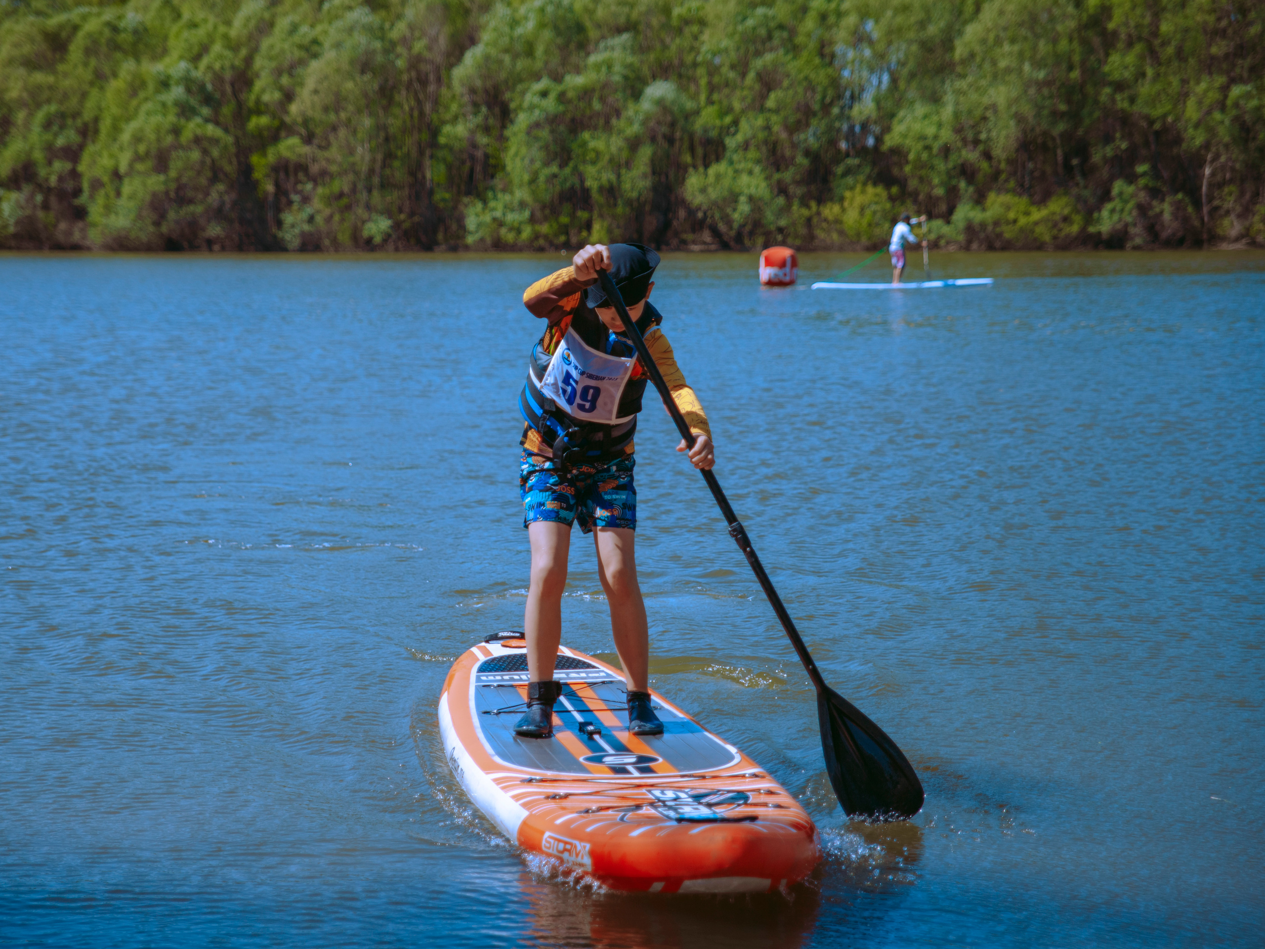 Мальчик на сапе подплывает к берегу.