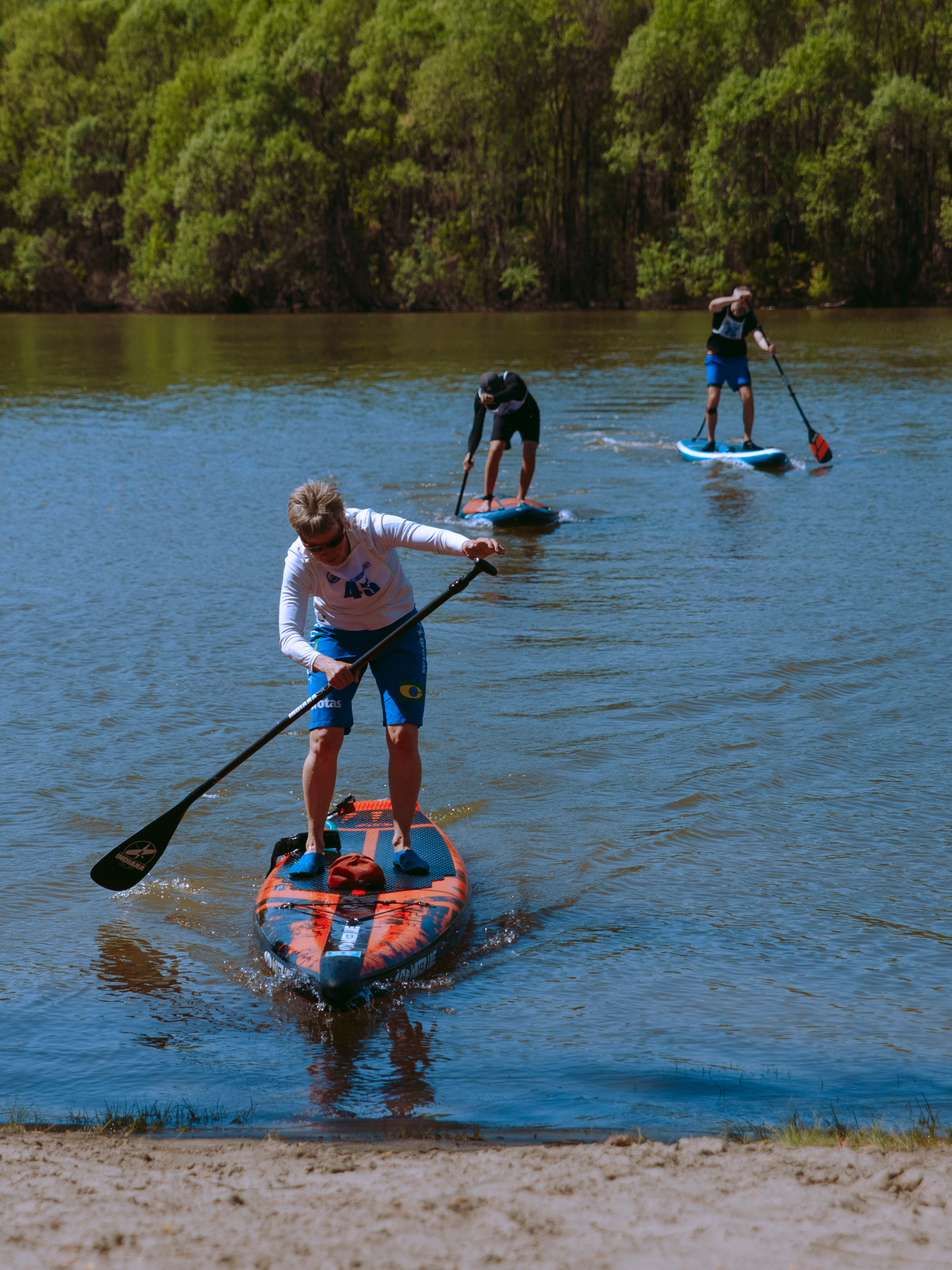 Люди плывут на сапах к берегу.