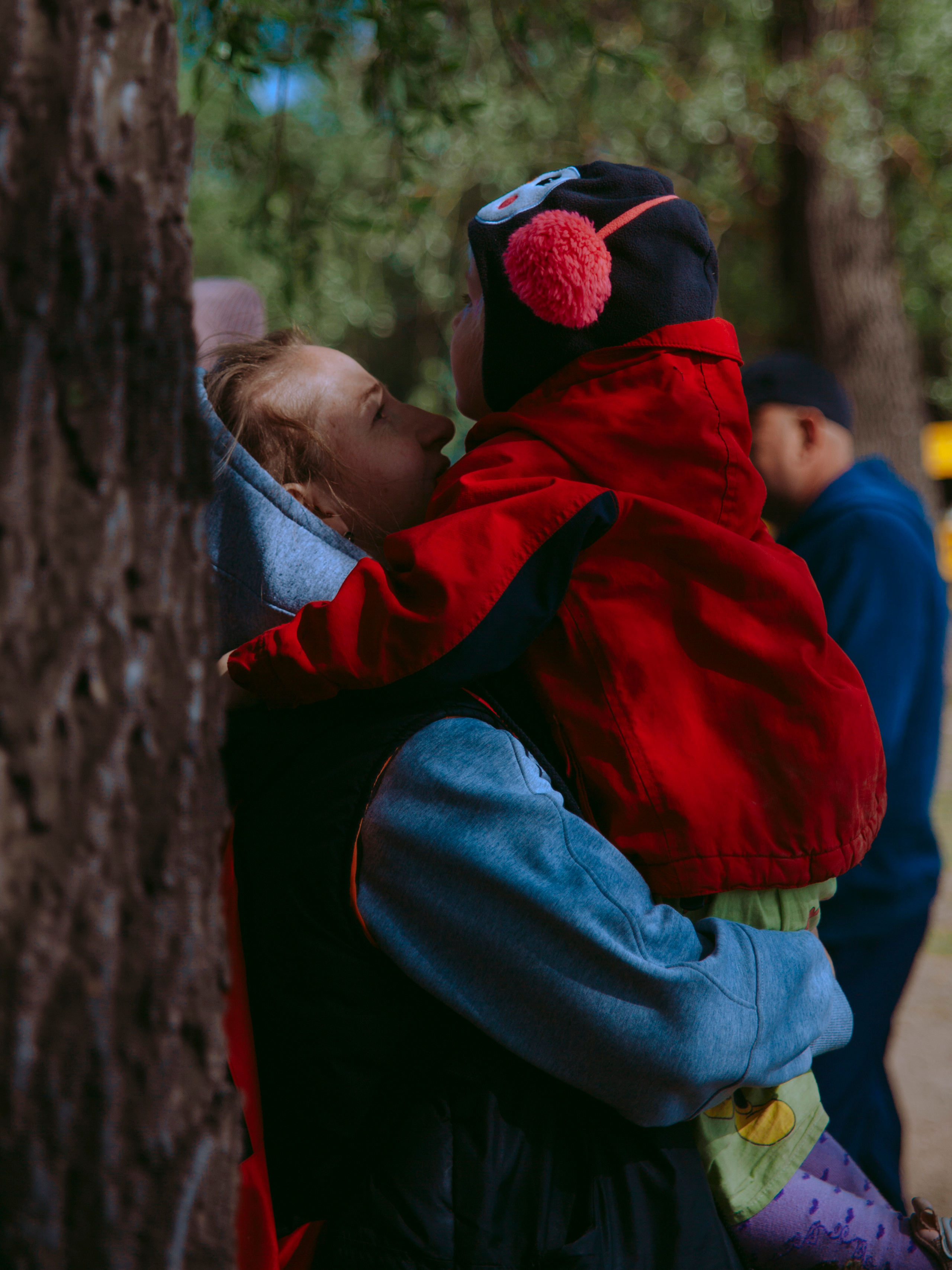 Мама держит на руках ребенка в смешной шапке.