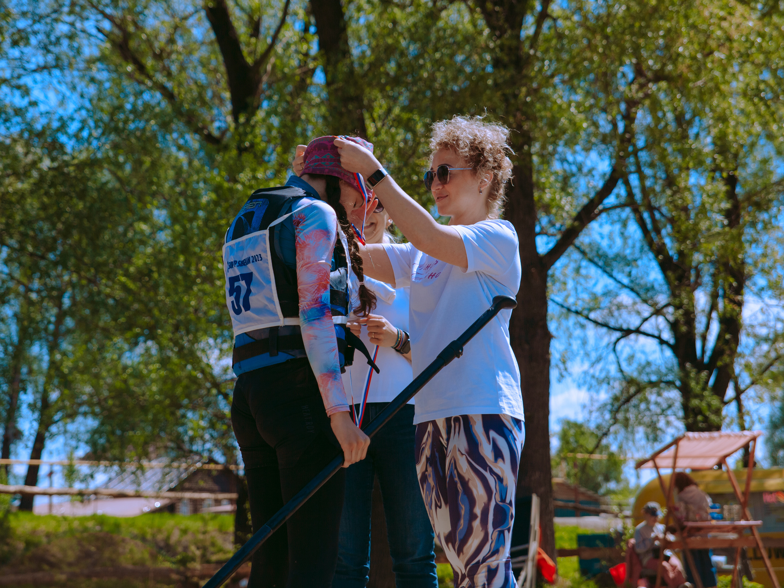 Женщина надевает медаль на спортсмена.