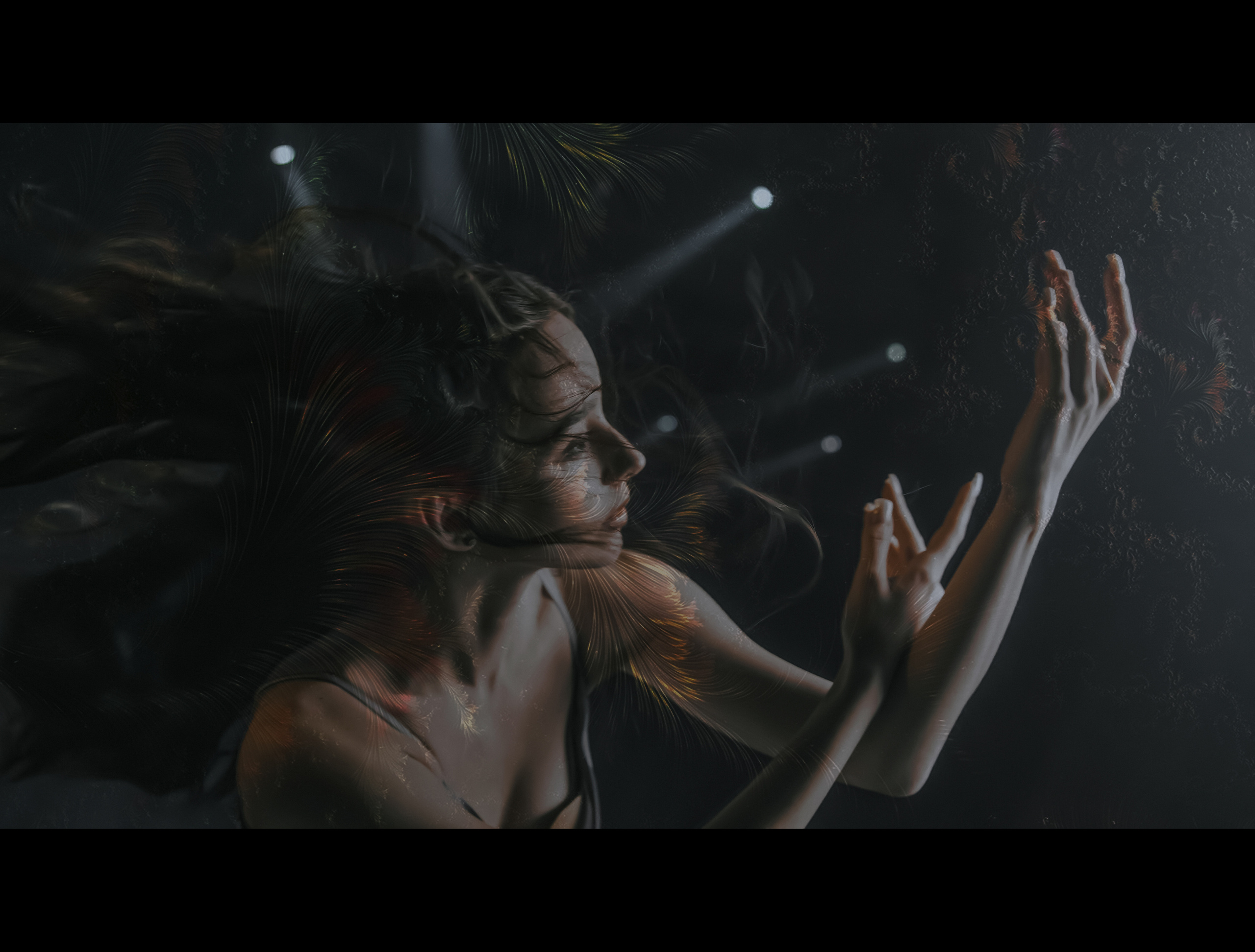 Девушка под светом софитов под водой.