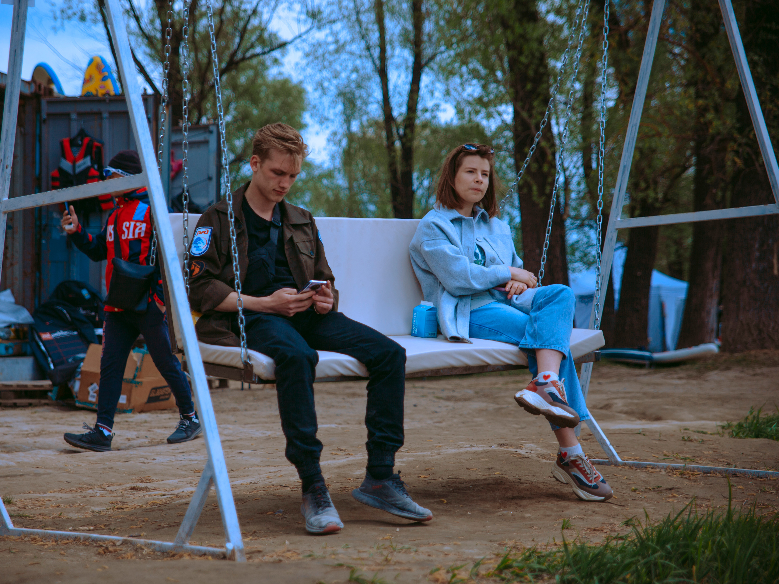 Парень с девушкой качаются на качелях.