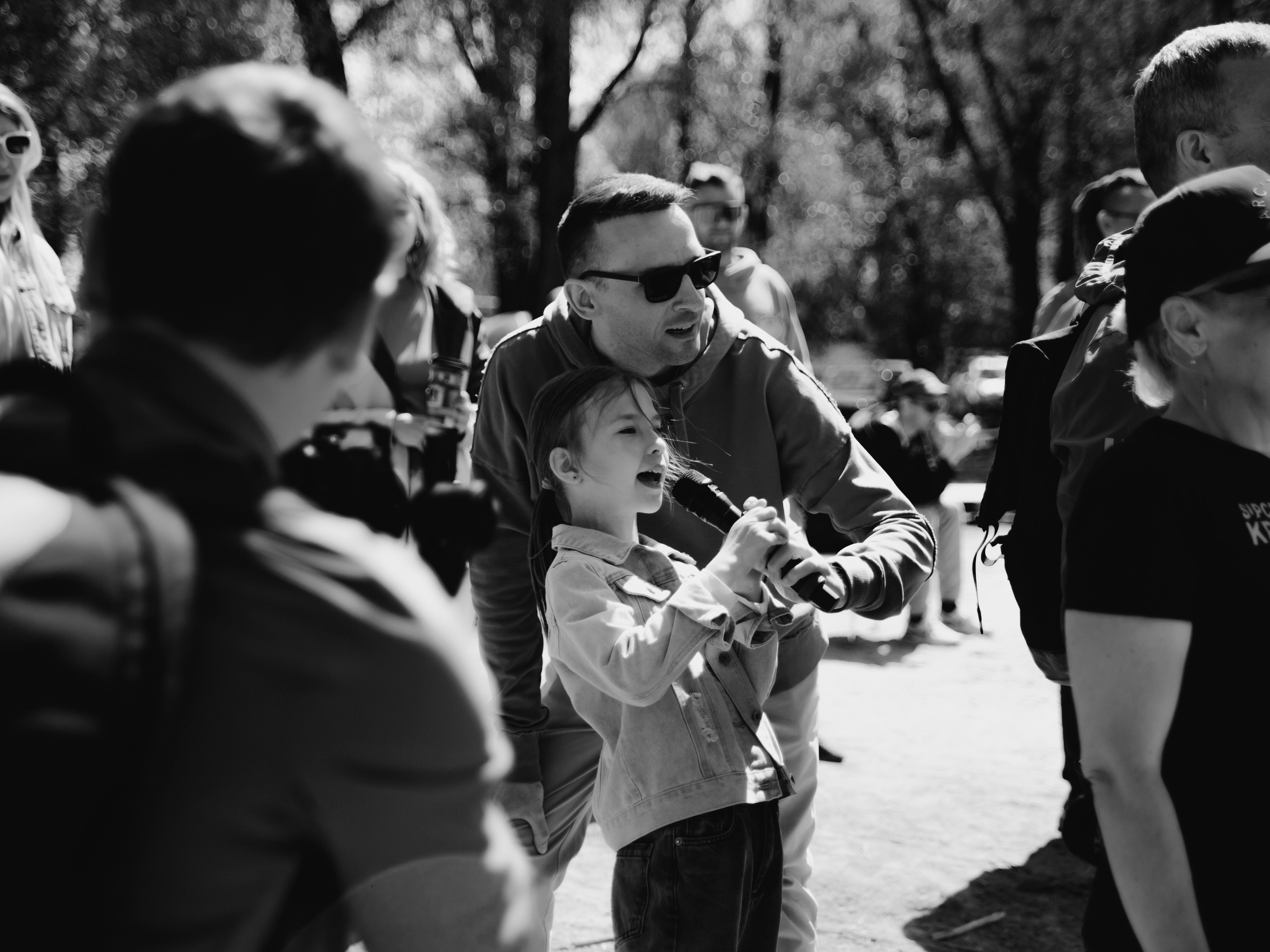 Маленькая девочка кричит в микрофон слова поддержки для папы.