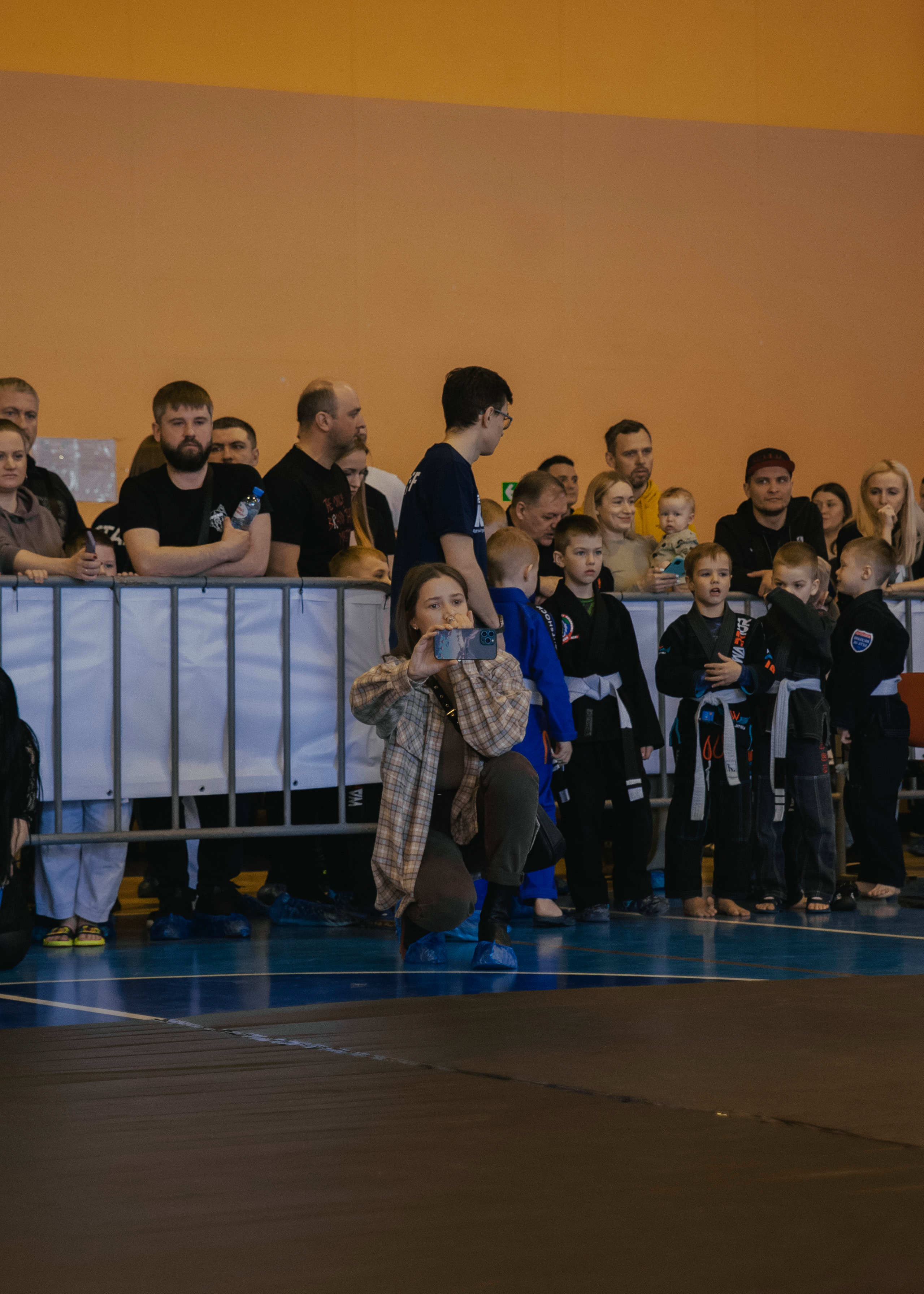Мама снимает на телефон на детском турнире по джиу-джитсу.