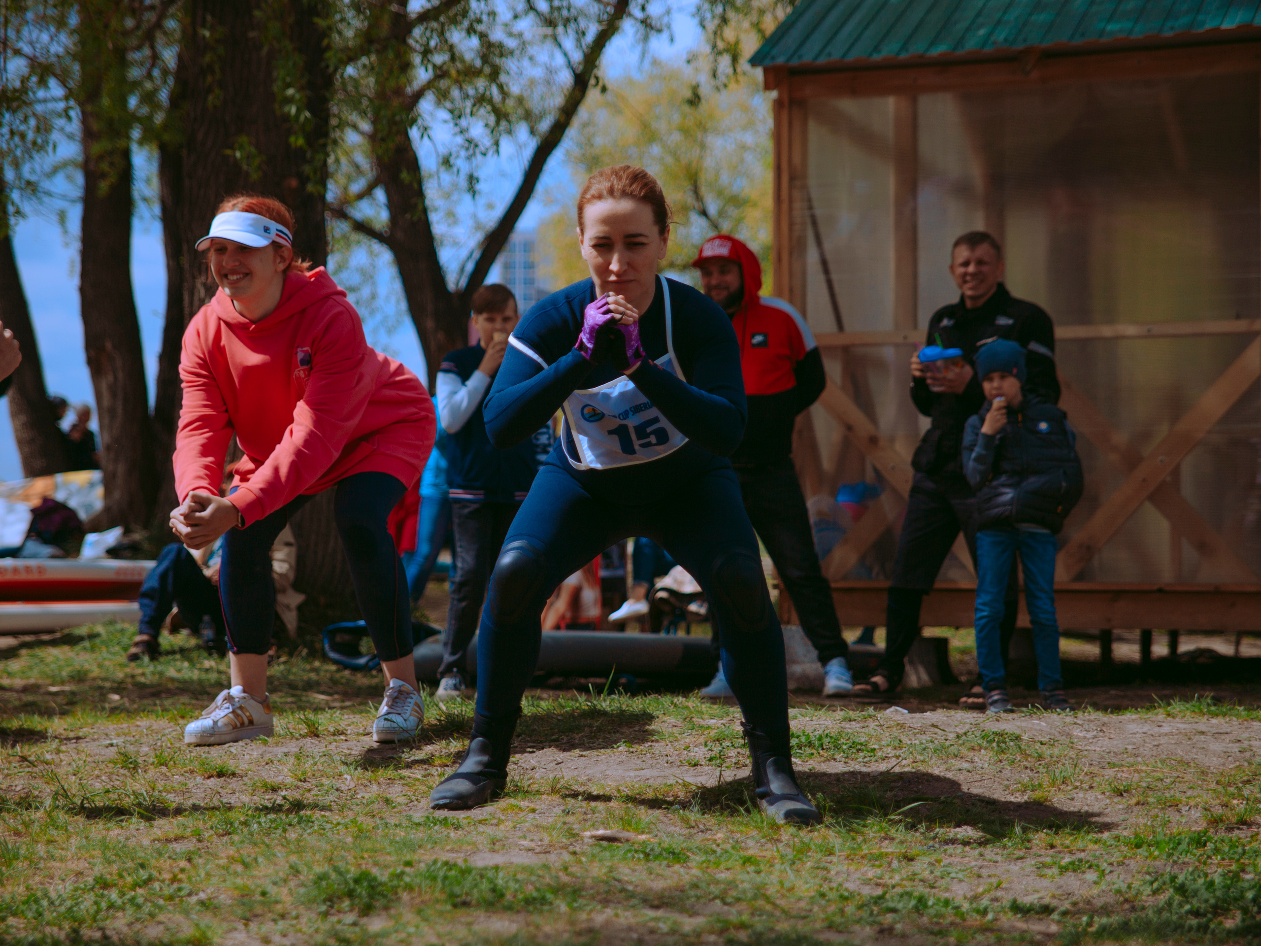 Женщина в гидрокостюме приседает в парке.