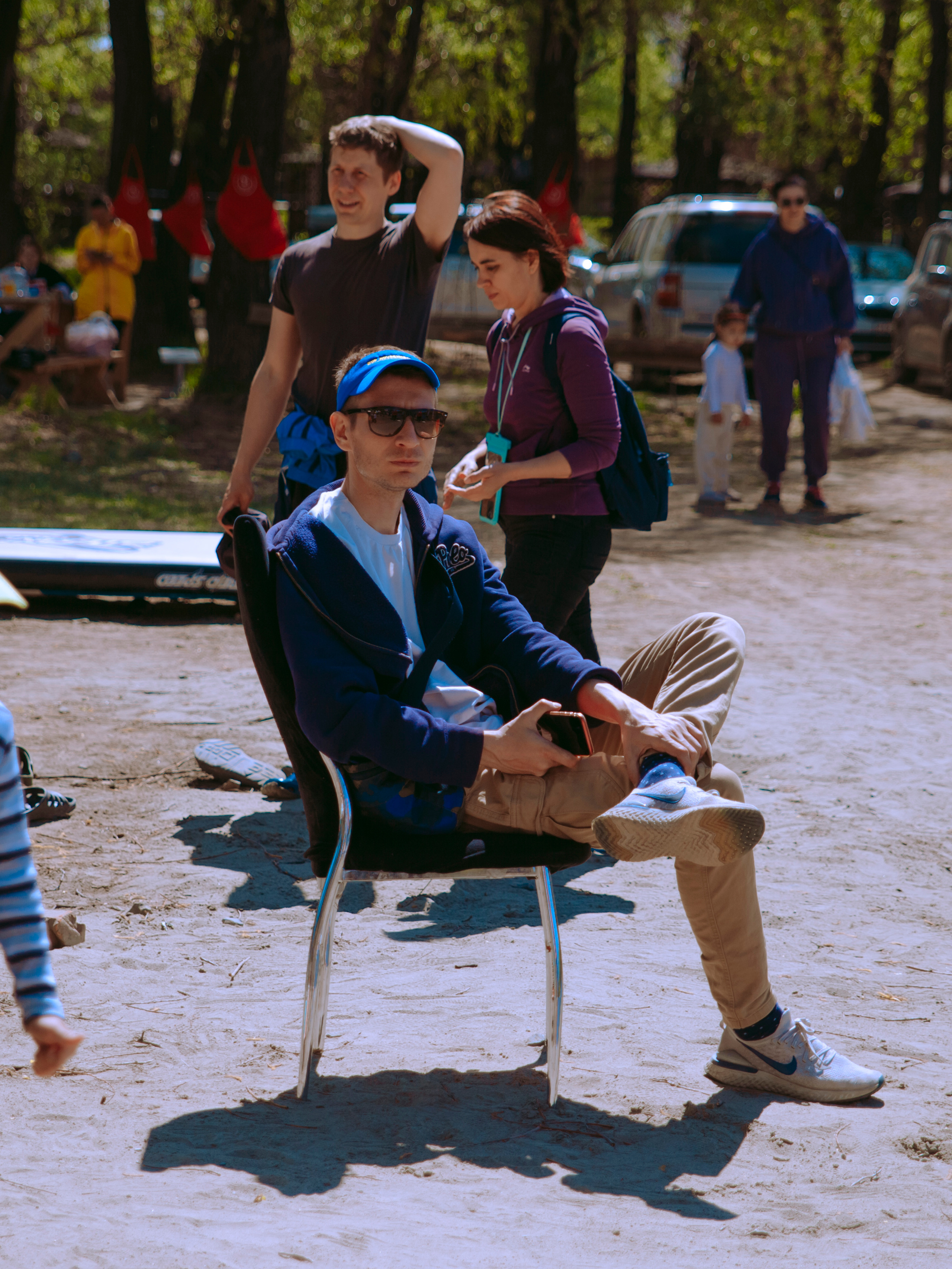 Мужчина сидит на берегу, закинув ногу на ногу.