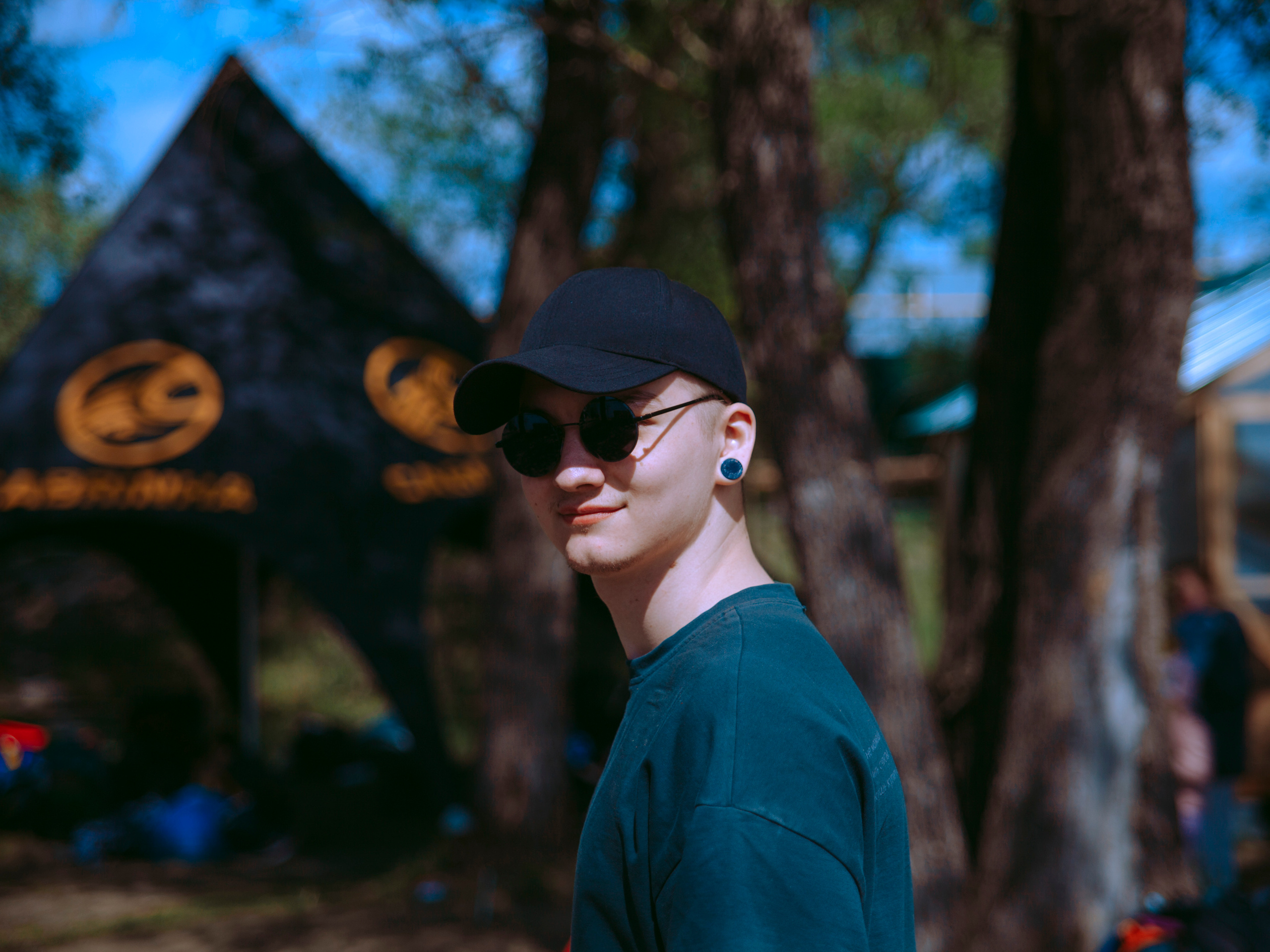 Парень в круглых очках смотрит в камеру.