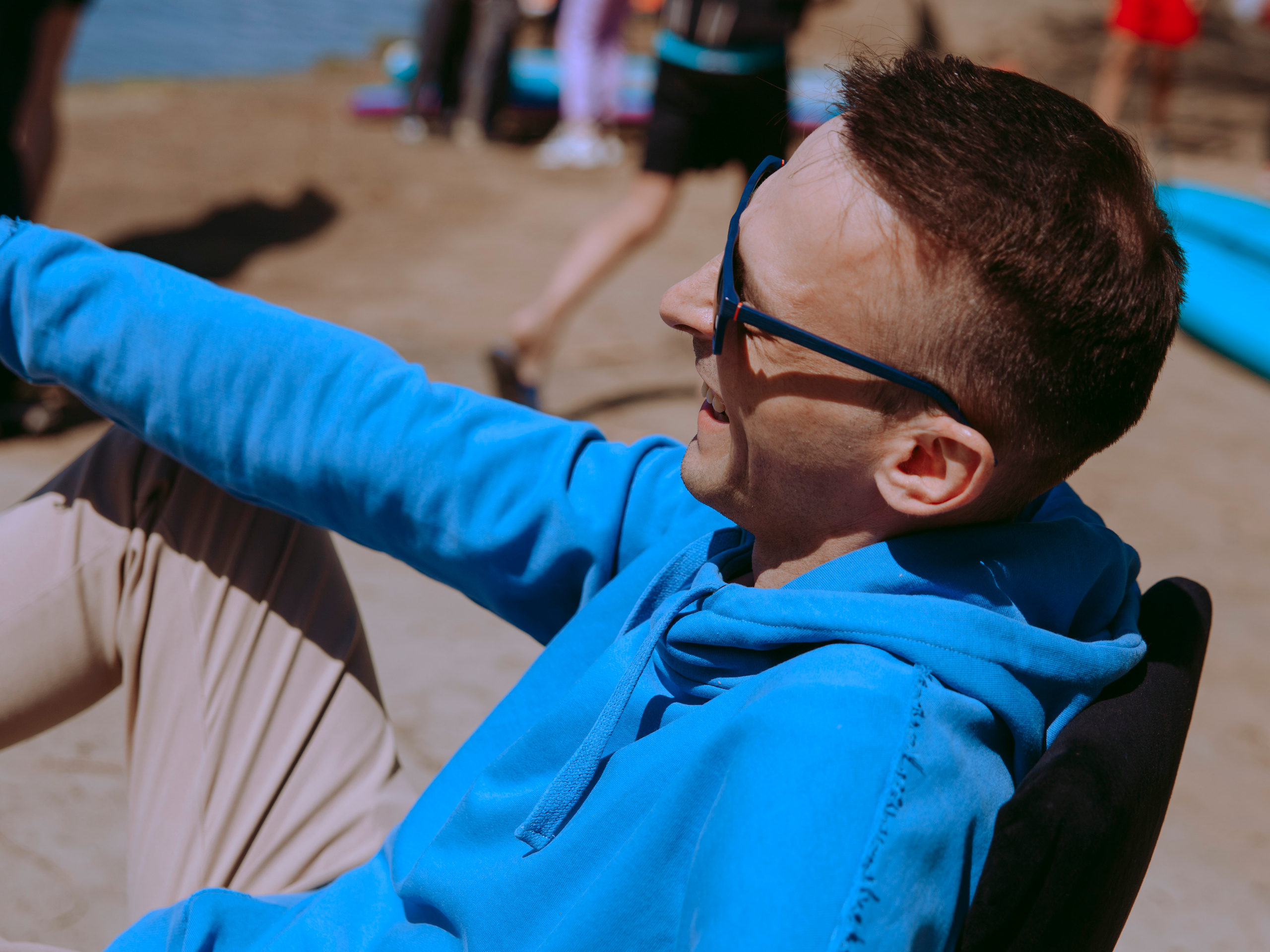 Ведущий мероприятия сидит на стуле в солнечный день.