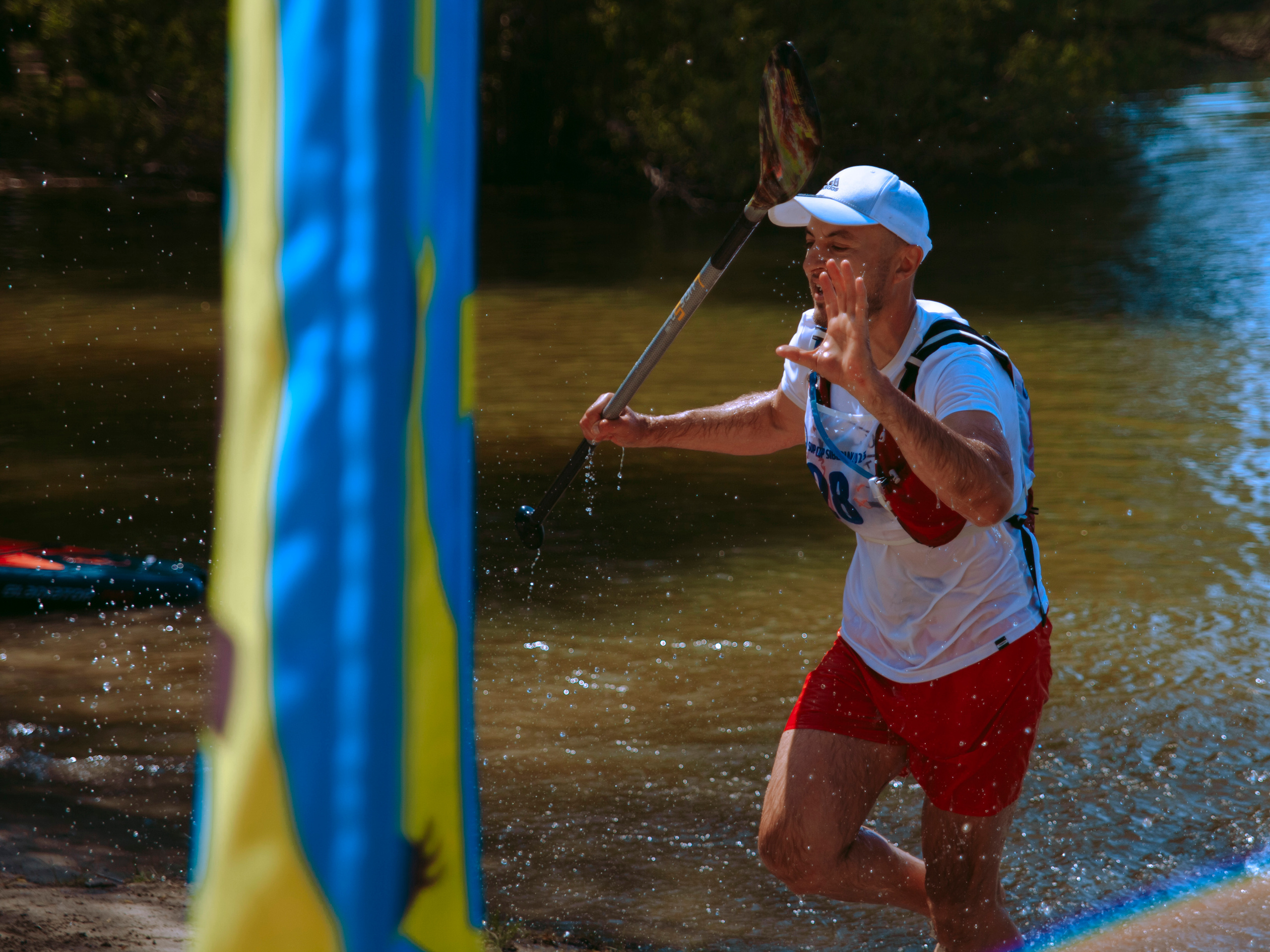 Мужчина бежит по воде с веслом в руке.
