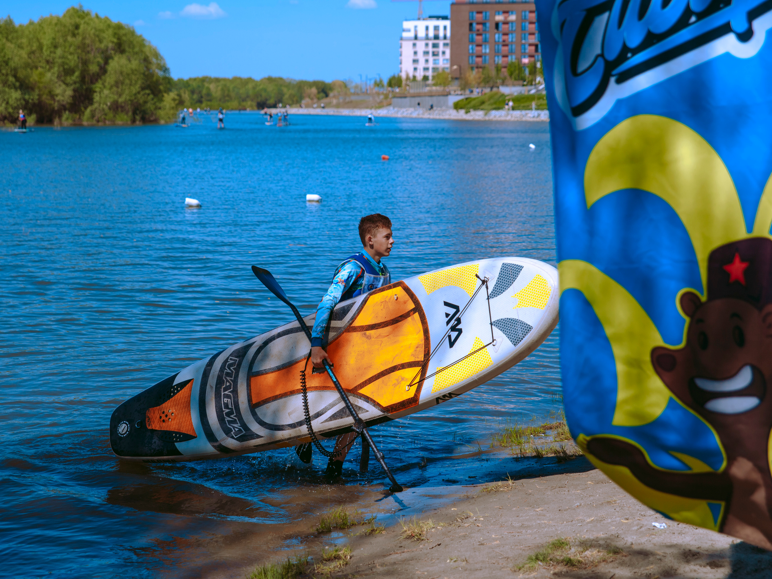 Спортсмен с сапом выходит из воды.