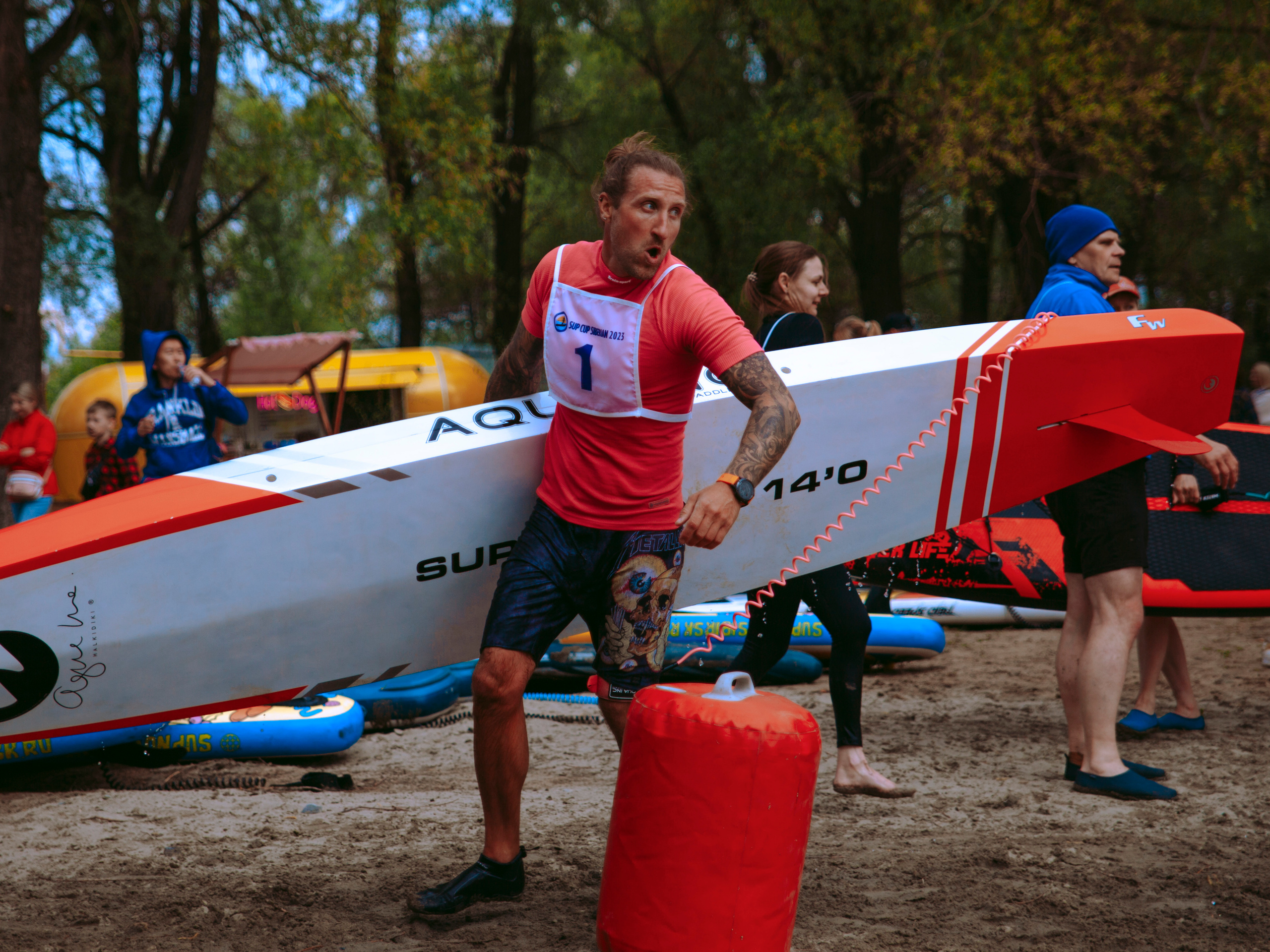 Красивый серфер бежит по берегу.