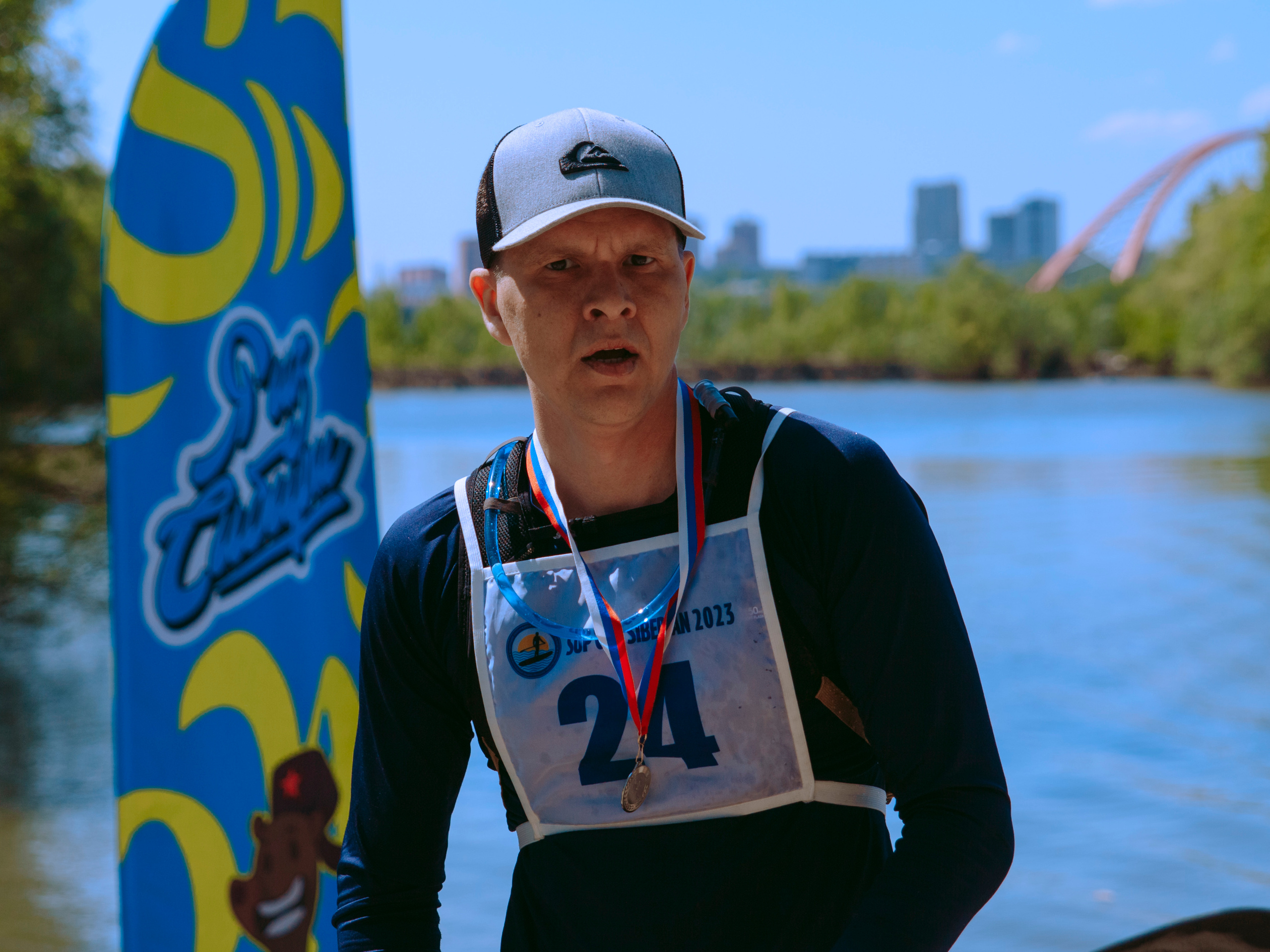 Парень в гидрокостюме с медалью.